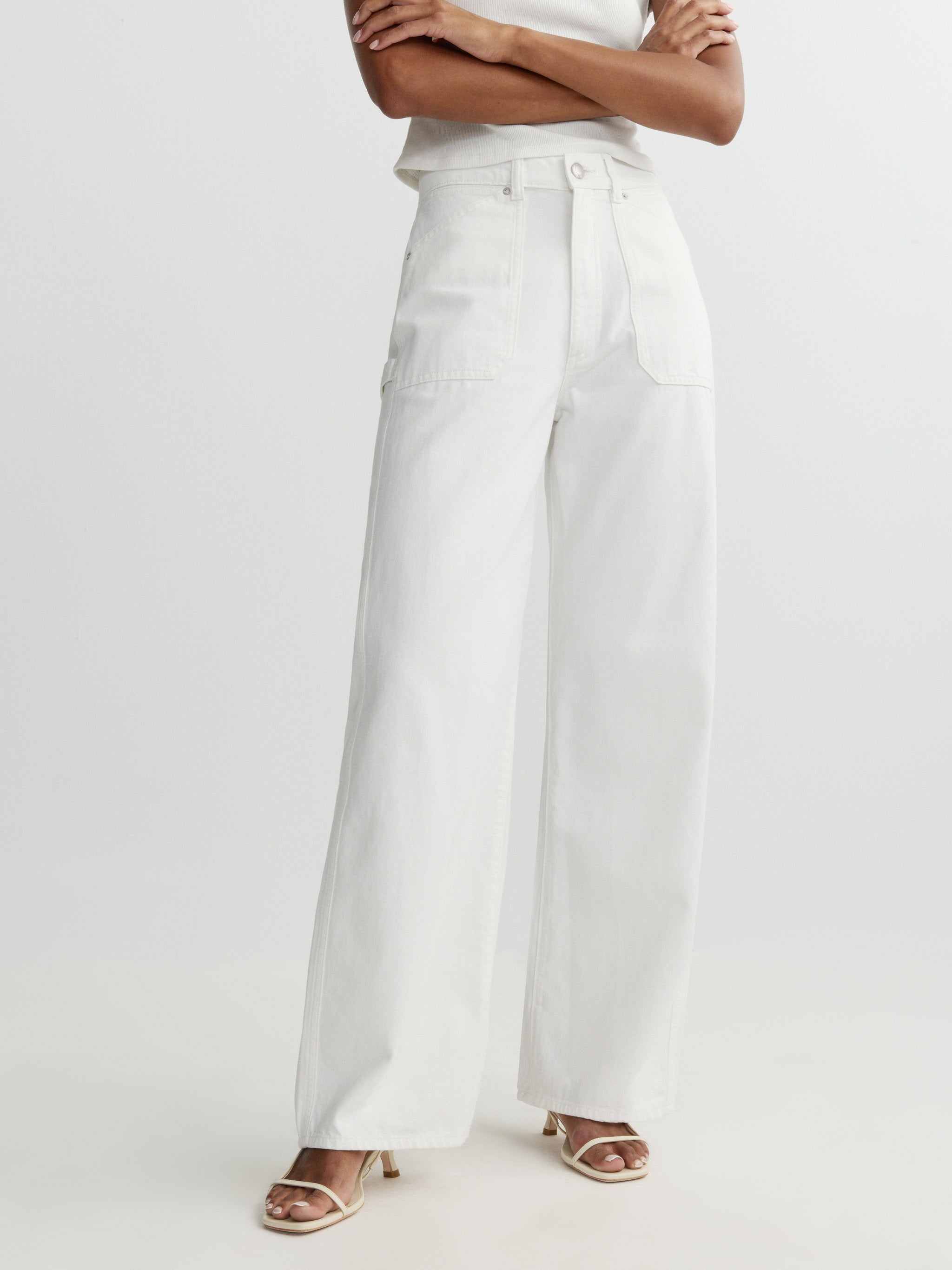 Person wearing a white sleeveless top and wide-leg pants on a light gray background