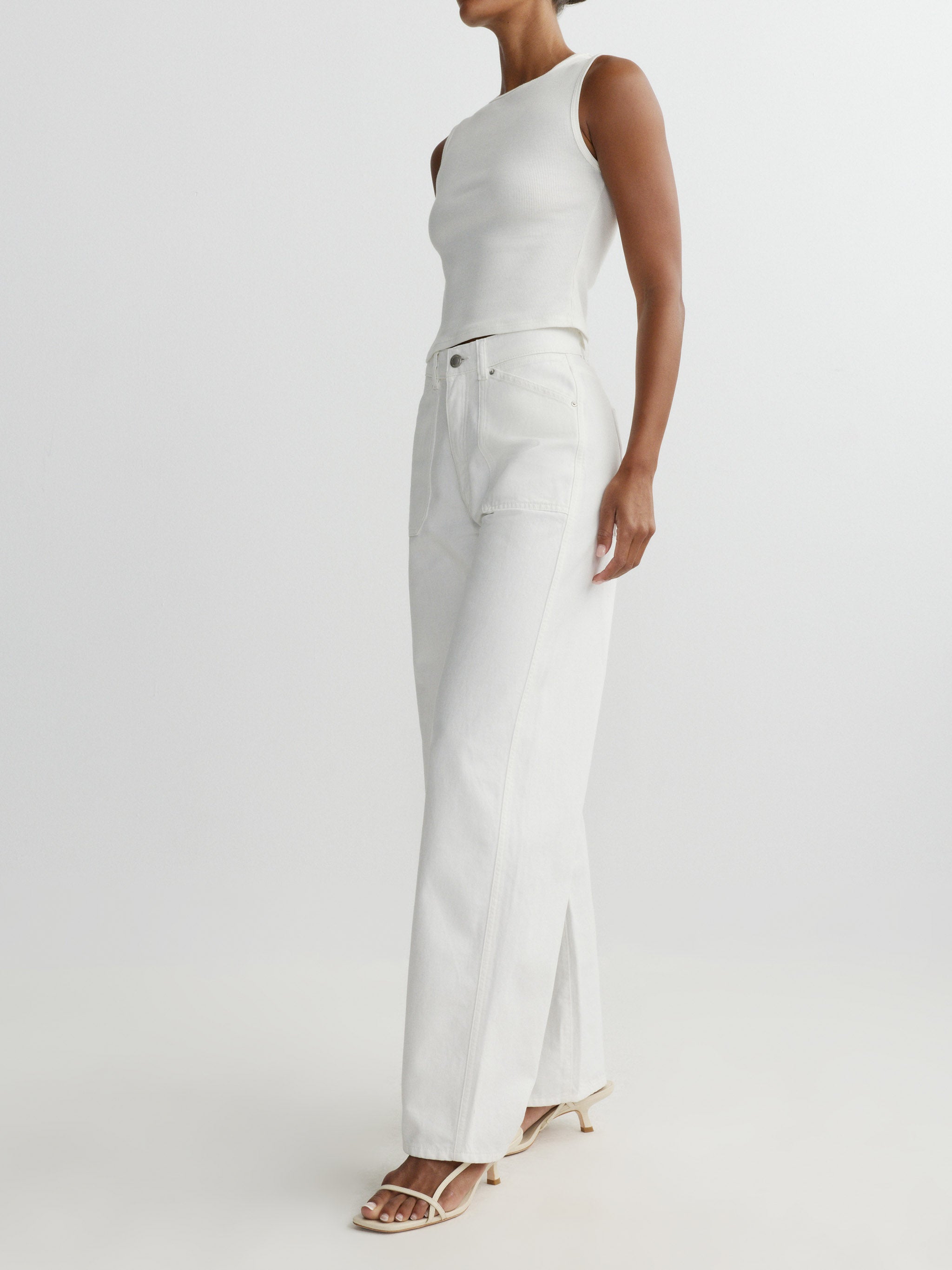 Person wearing a white sleeveless top and pants on a light gray background