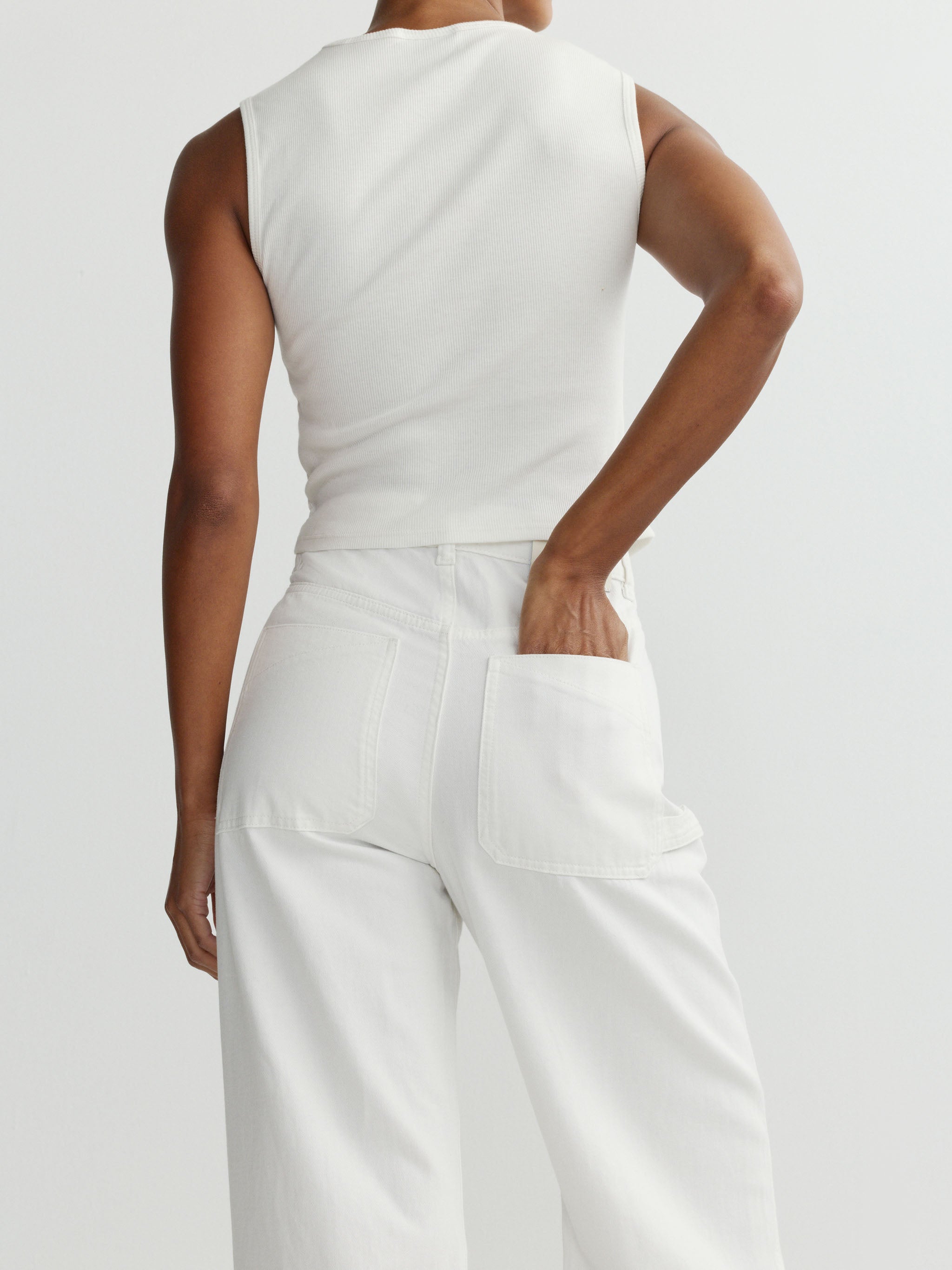 Person wearing a white sleeveless top and pants on a plain background