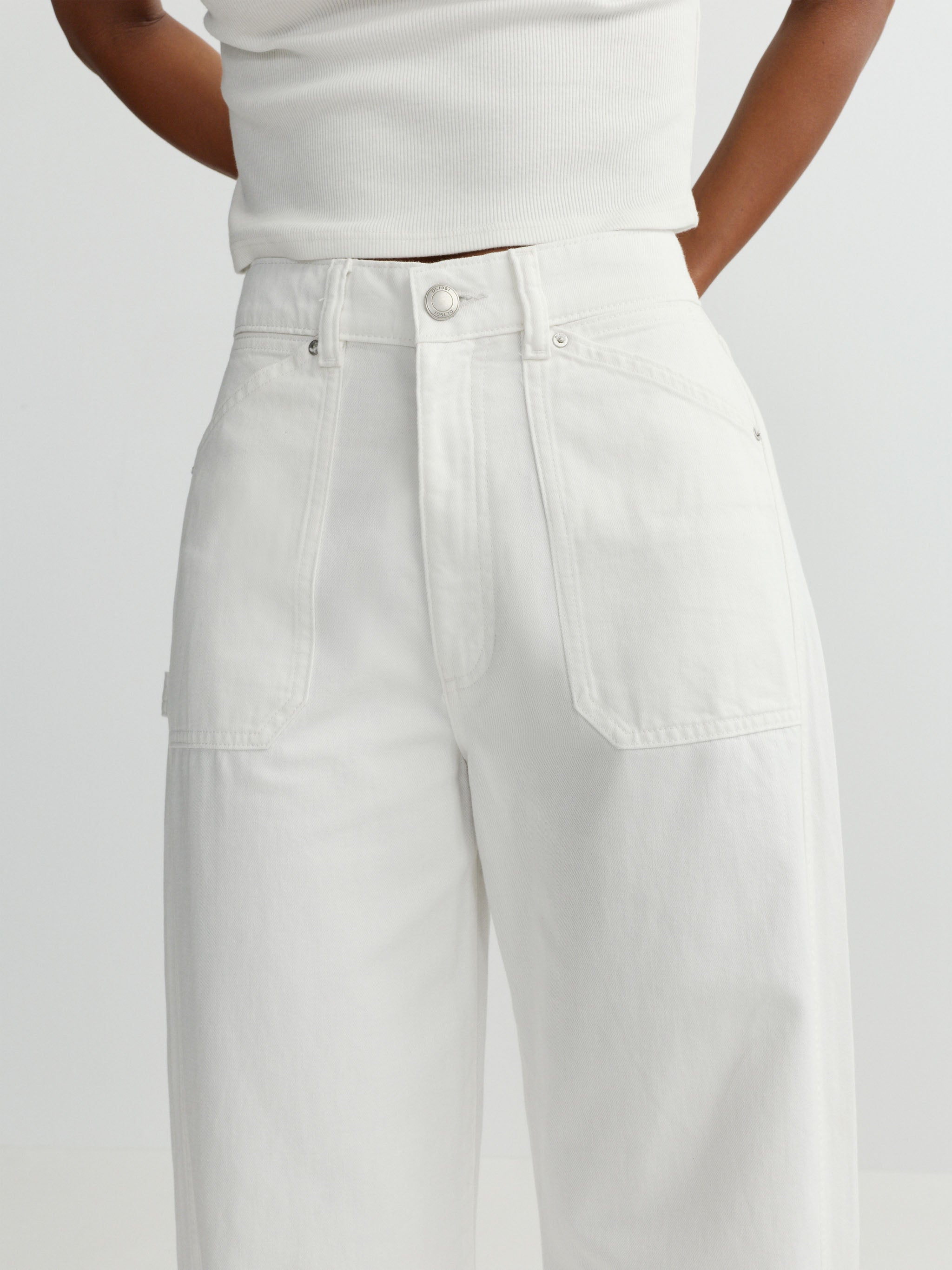 Person wearing a white sleeveless top and wide-leg pants on a light gray background