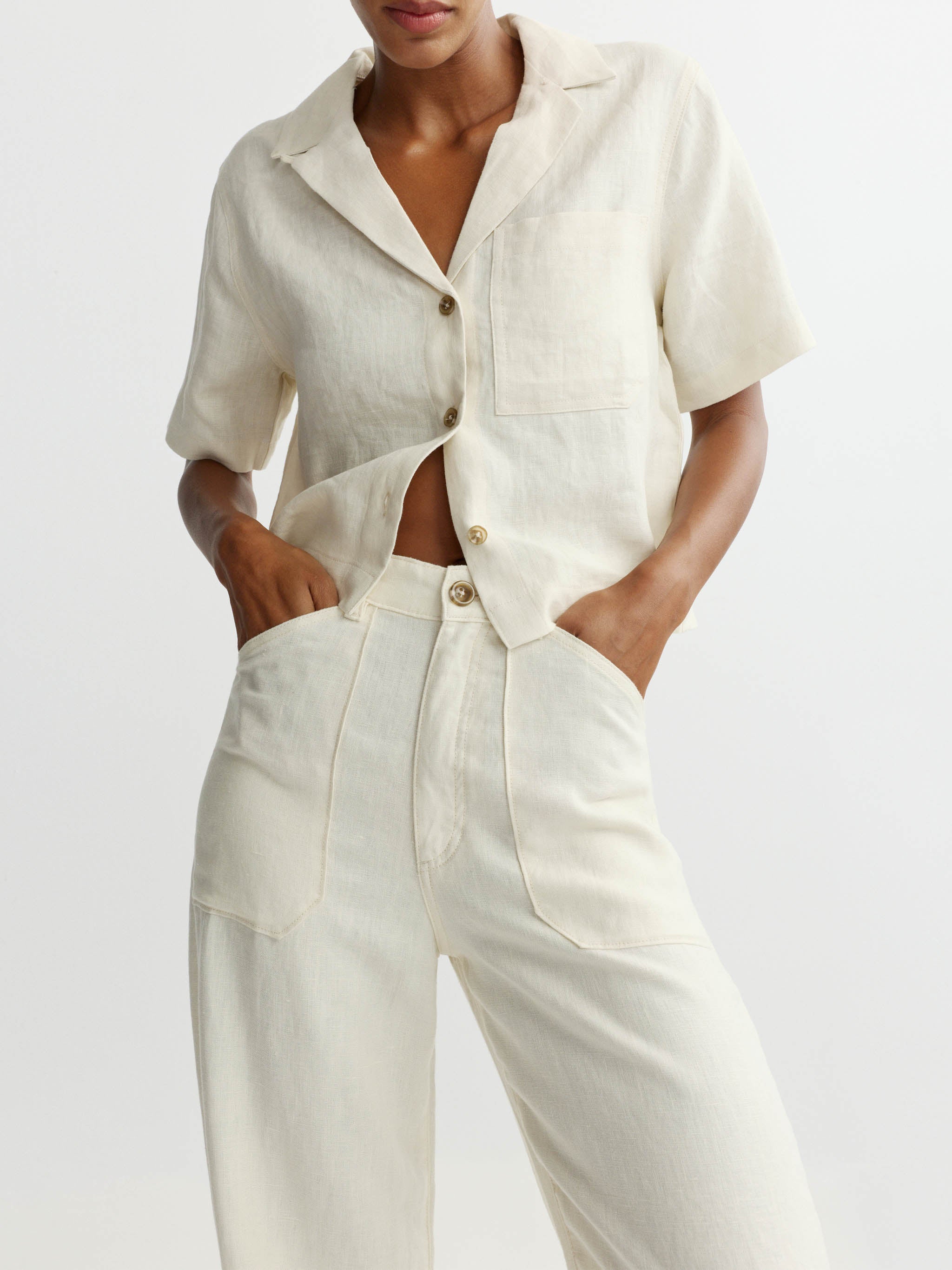 Person wearing a white outfit with a shirt and pants on a plain background