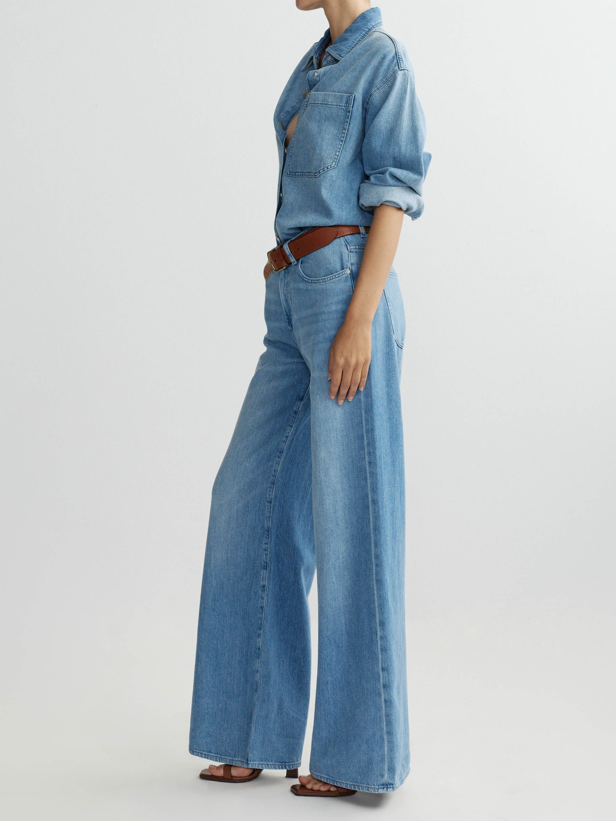 Person wearing a denim outfit with wide-leg jeans on a light gray background