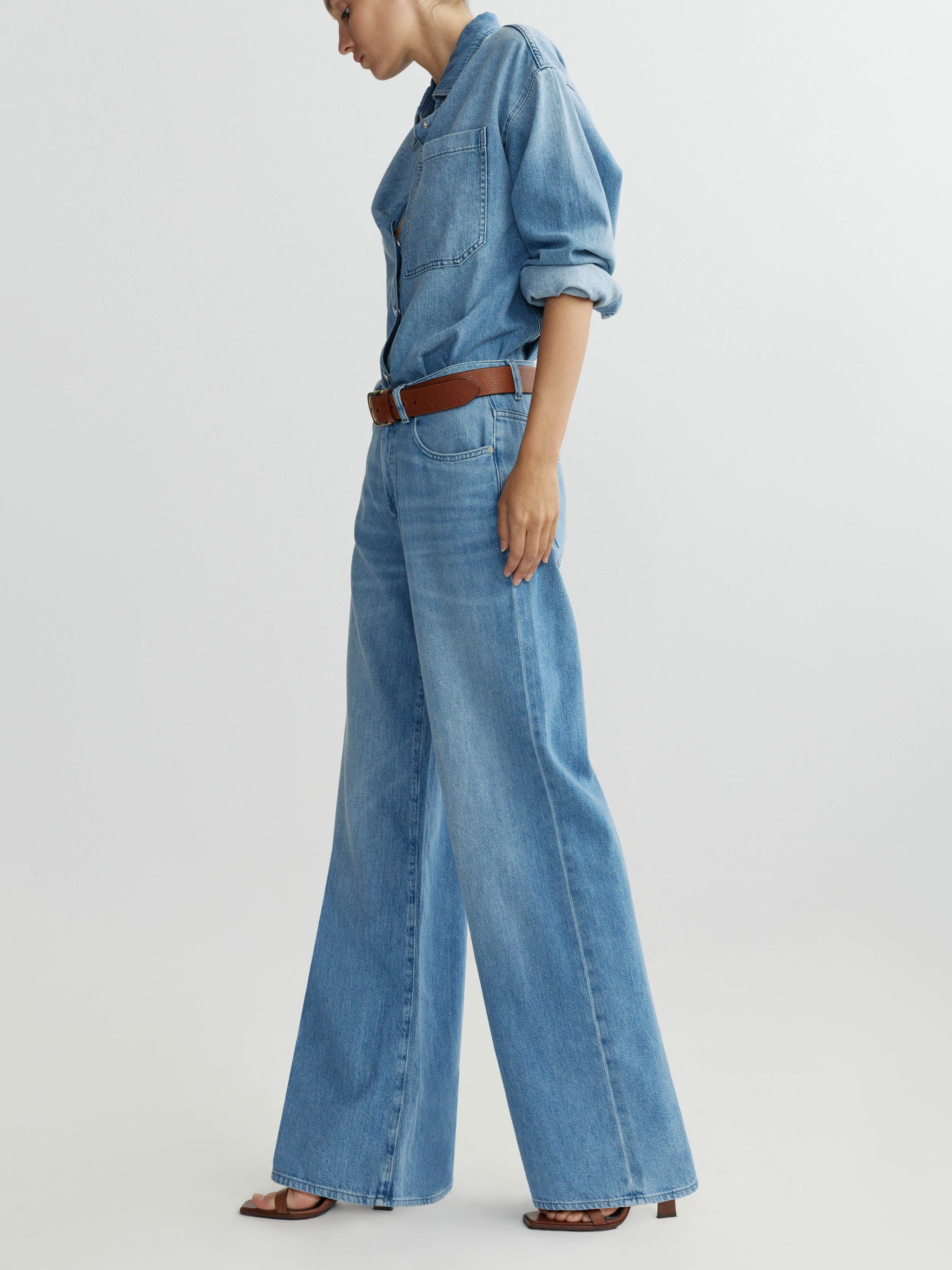 Person wearing a denim outfit with wide-leg jeans on a plain background