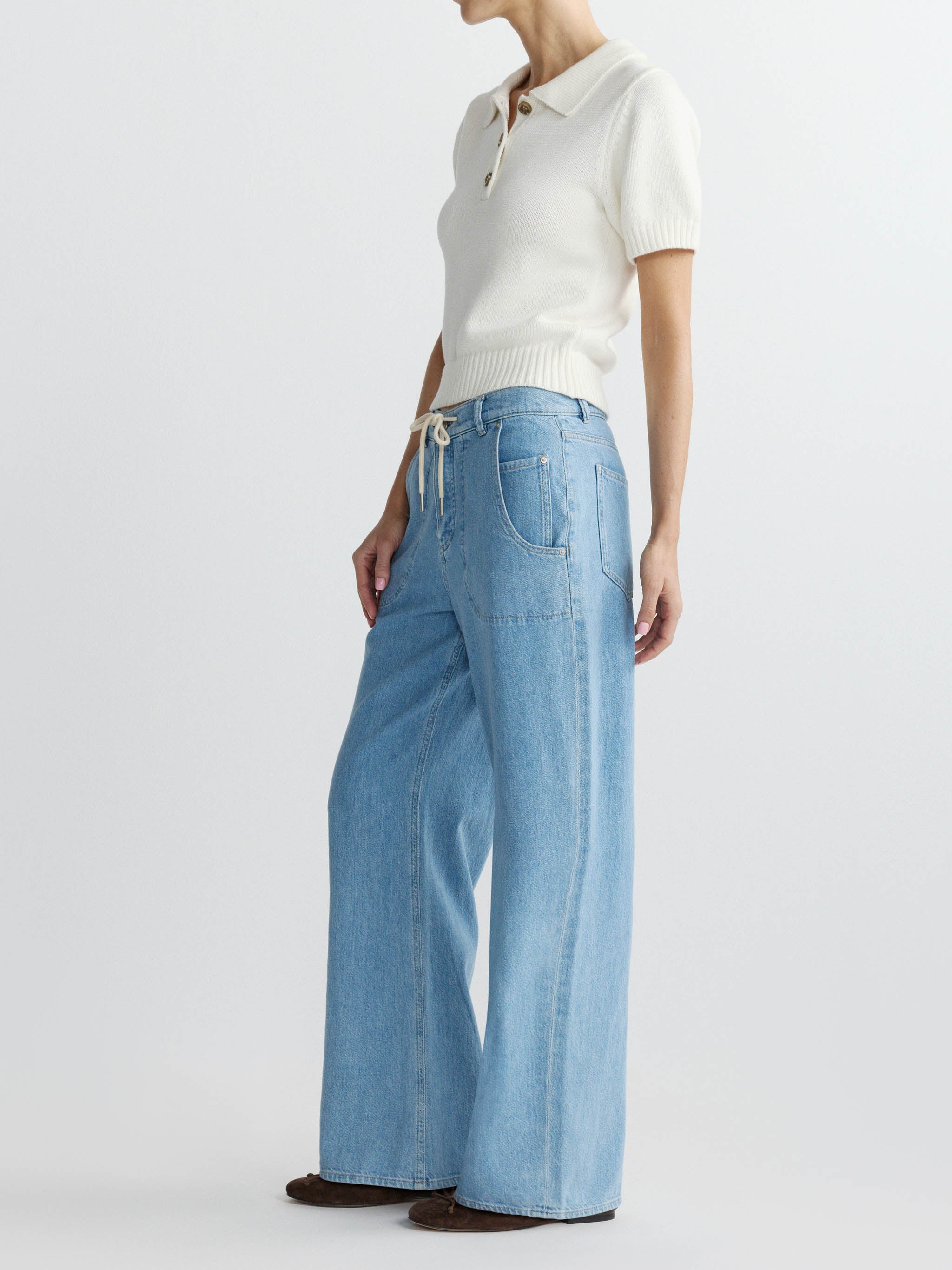 Person wearing a white polo shirt and light blue jeans on a white background