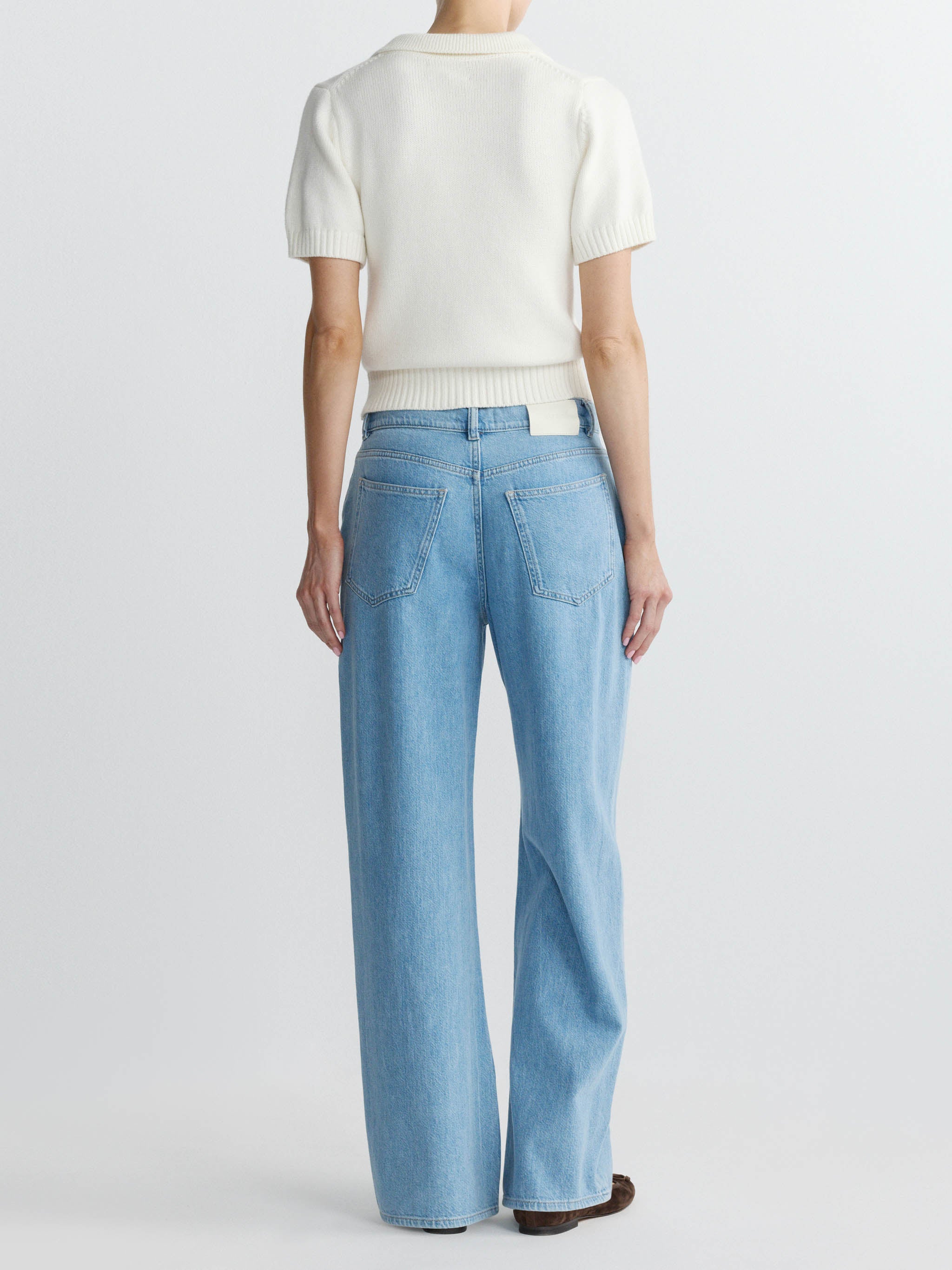 Person wearing a white top and light blue jeans on a white background