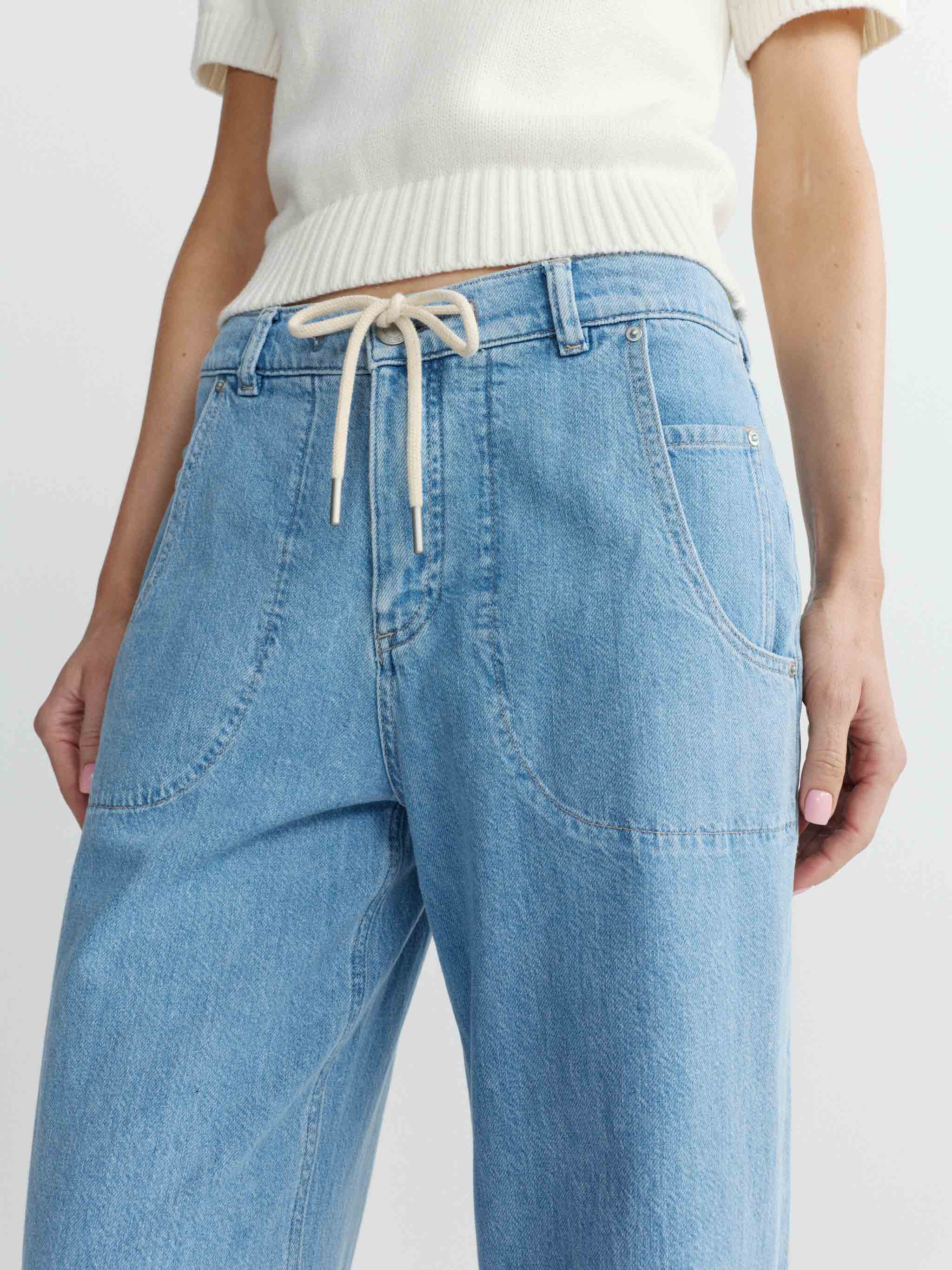 Light blue jeans with a drawstring waist on a white background