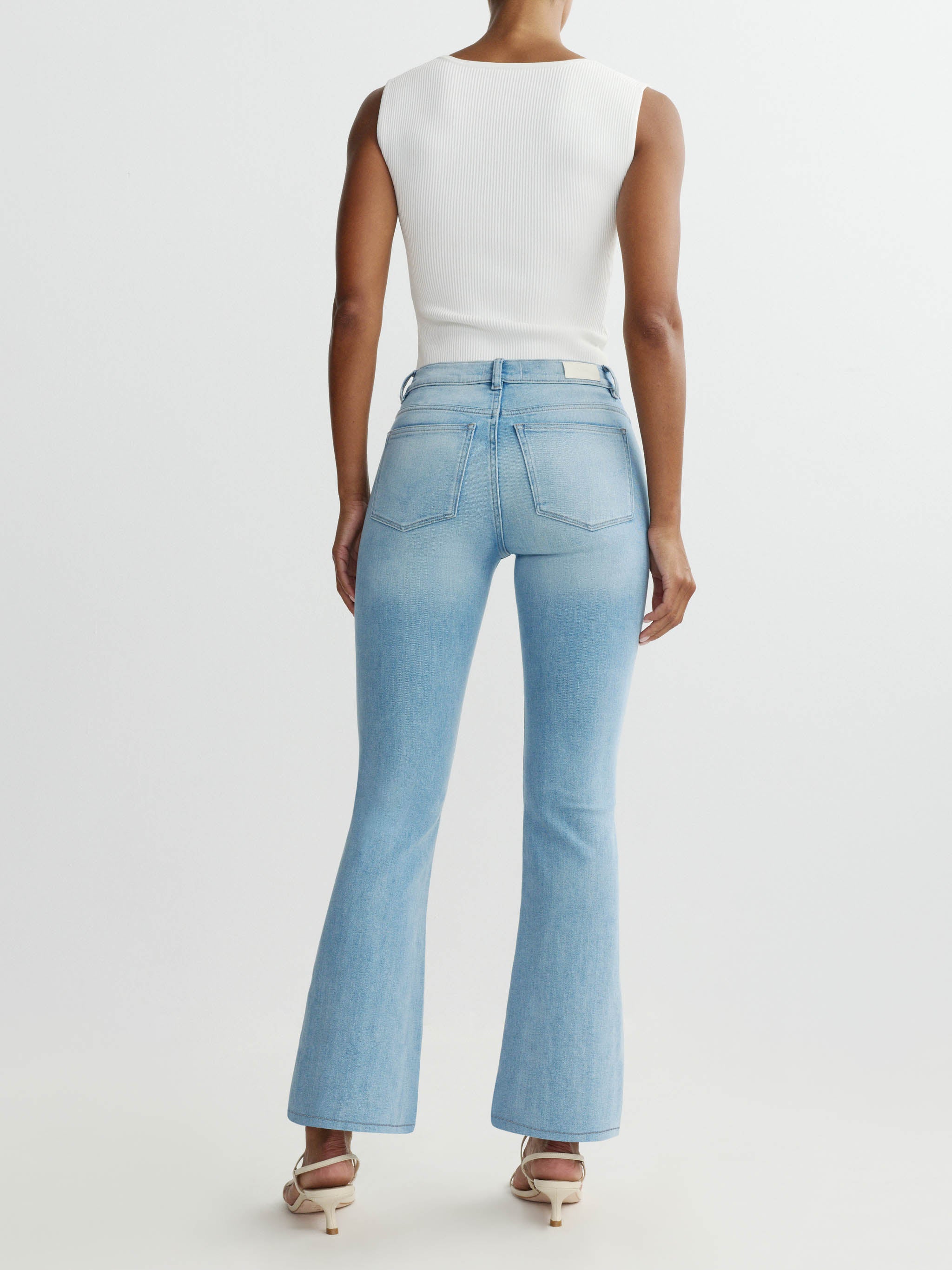 Person wearing light blue jeans and a white top on a white background