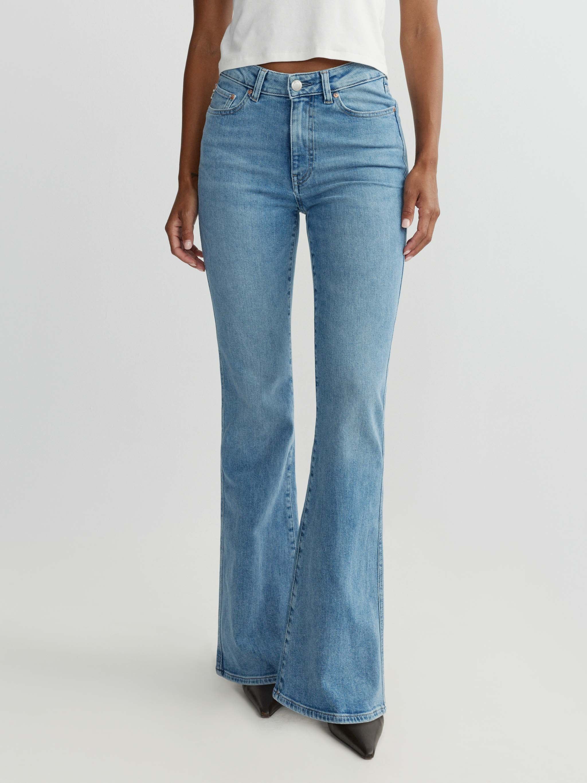 Blue flared jeans worn by a person on a white background