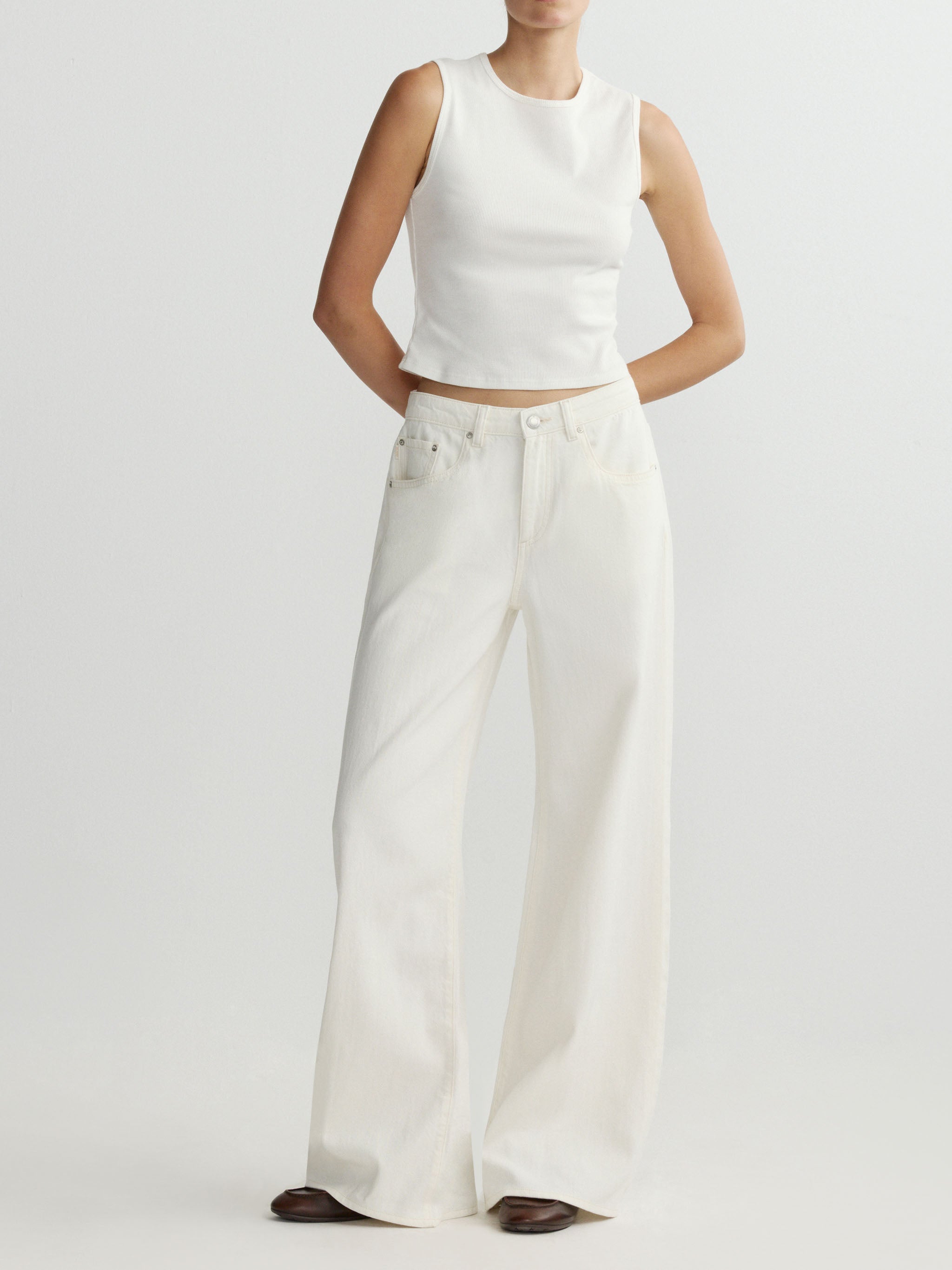 Person wearing a white sleeveless top and wide-leg pants on a light gray background