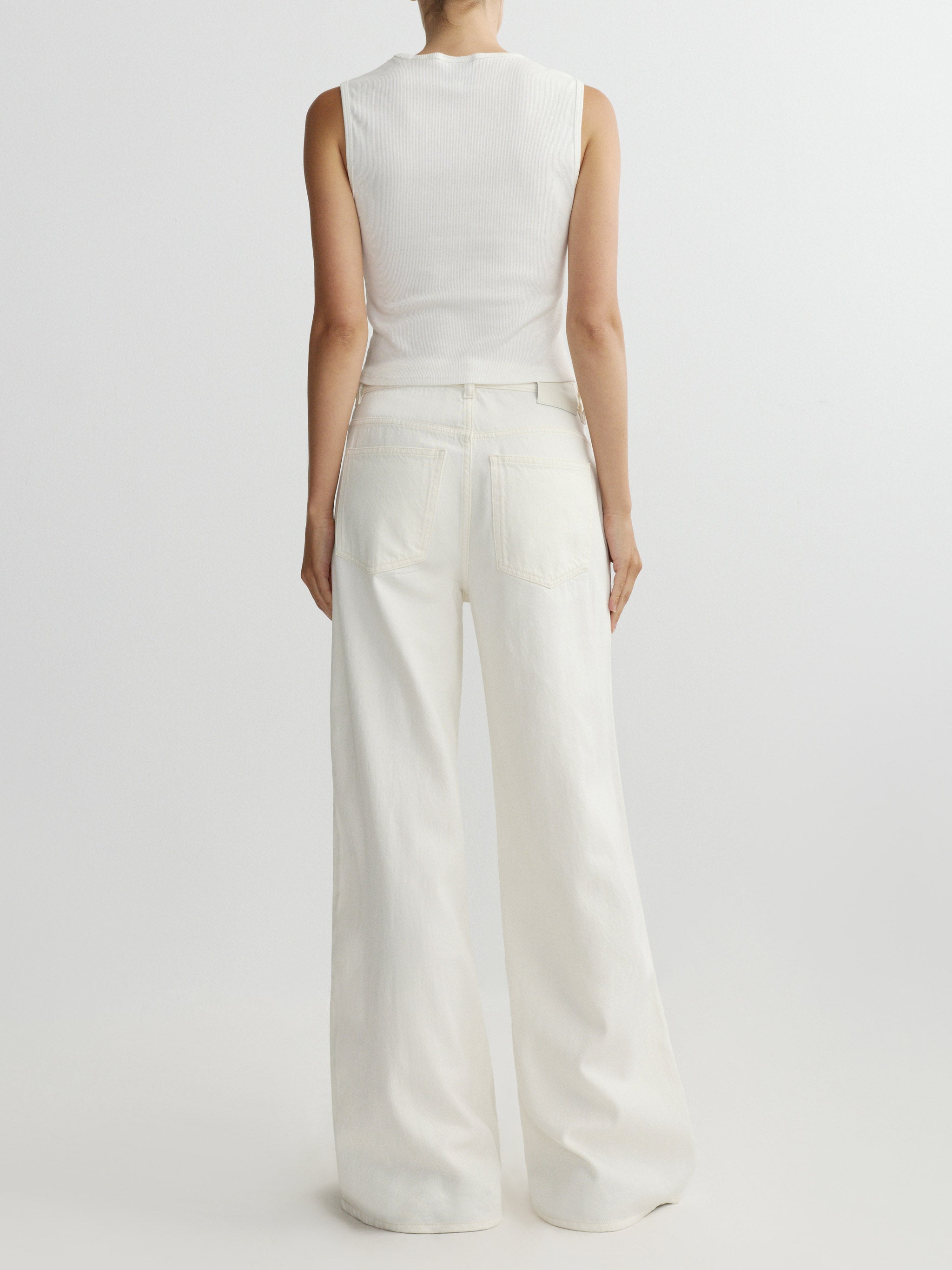 Person wearing a white sleeveless top and wide-leg pants on a light gray background