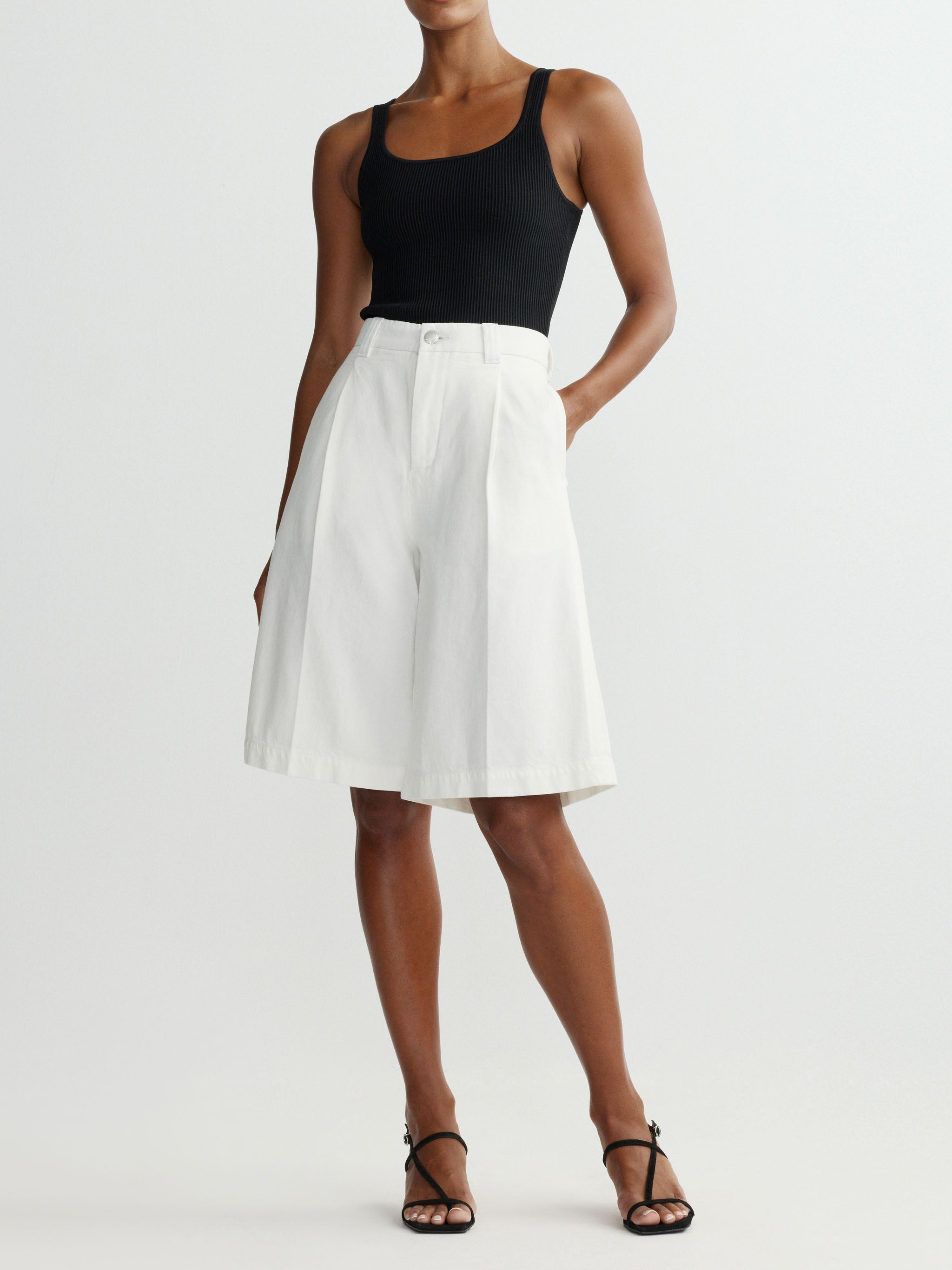 Person wearing a black tank top and white shorts on a plain background