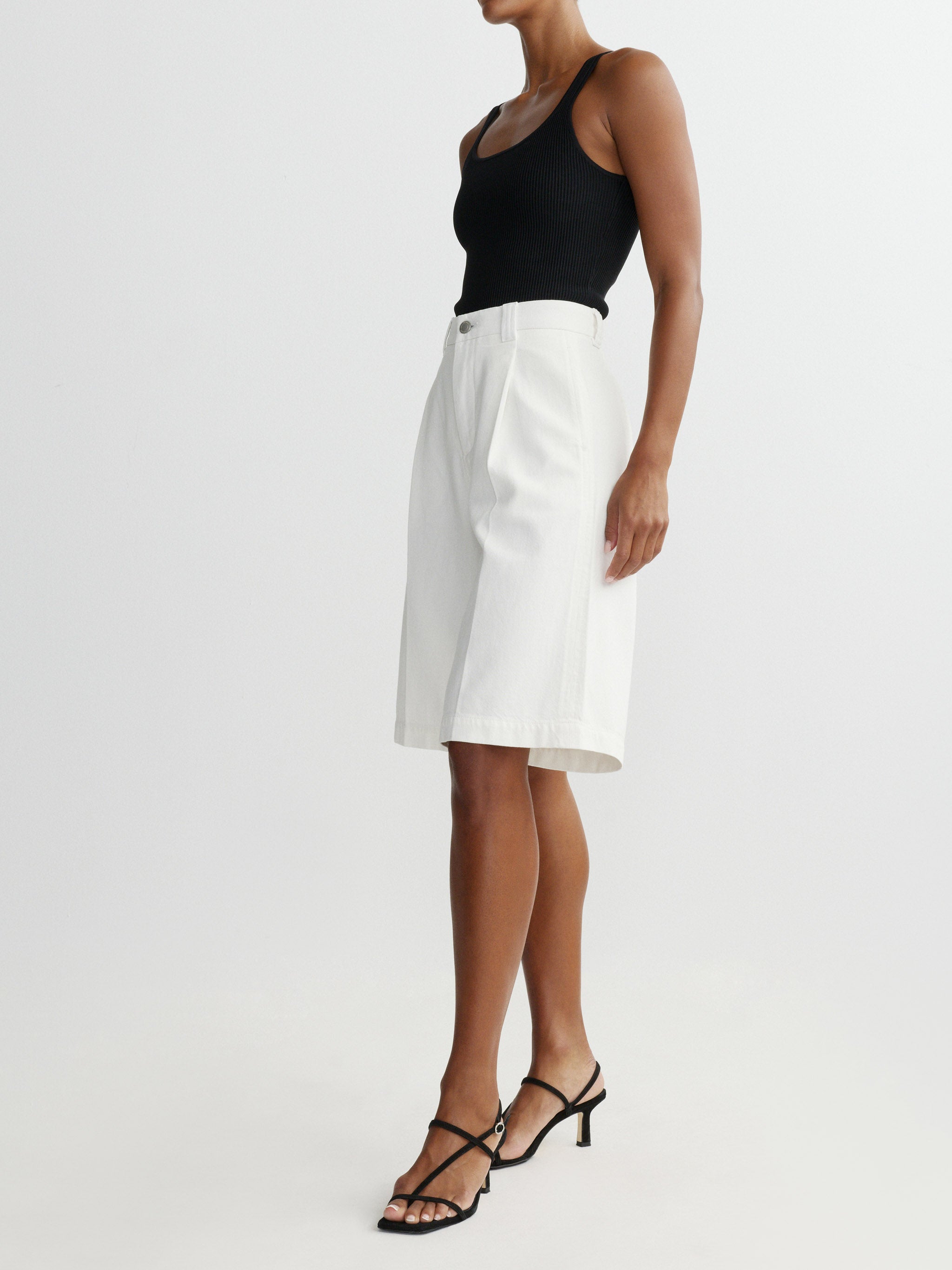 Person wearing a black tank top and white short on a light gray background