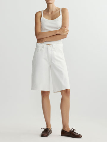 Person wearing a white sleeveless top and white shorts on a plain background