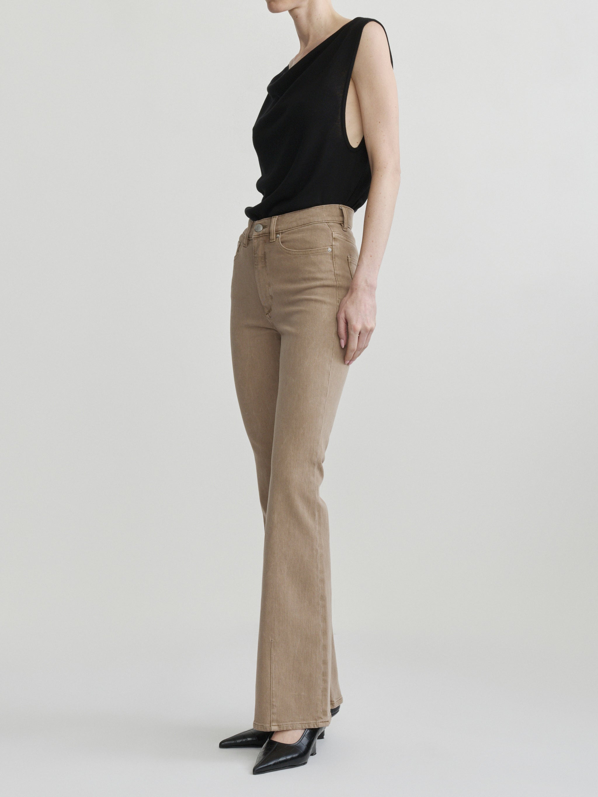 Bridget Boot jeans in Desert with the Defined Flow Top in Black, full-length side view in a studio.