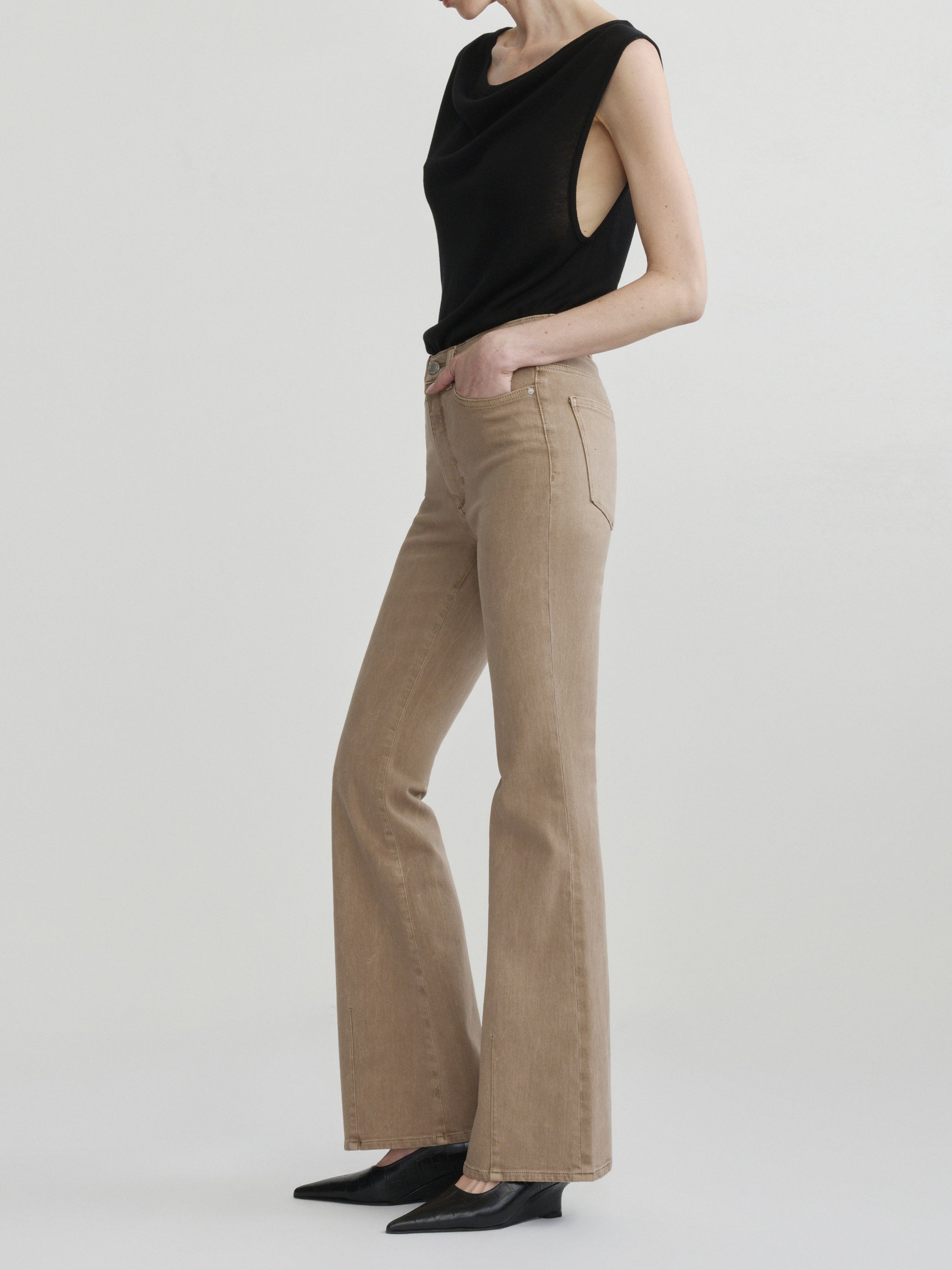 Bridget Boot jeans in Desert with the Defined Flow Top in Black, full-length side view in a studio.