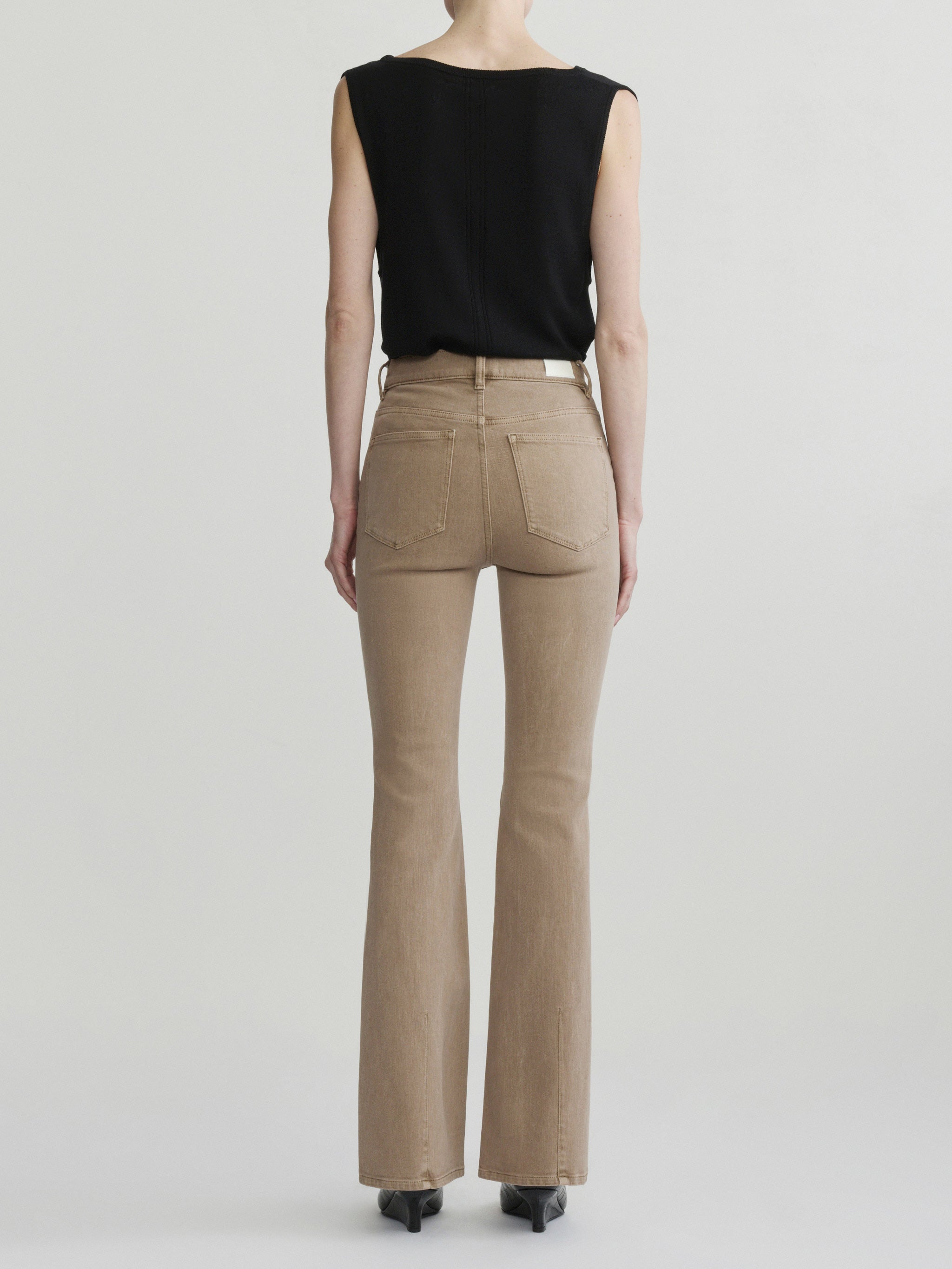 Bridget Boot jeans in Desert with the Defined Flow Top in Black, full-length back view in a studio.