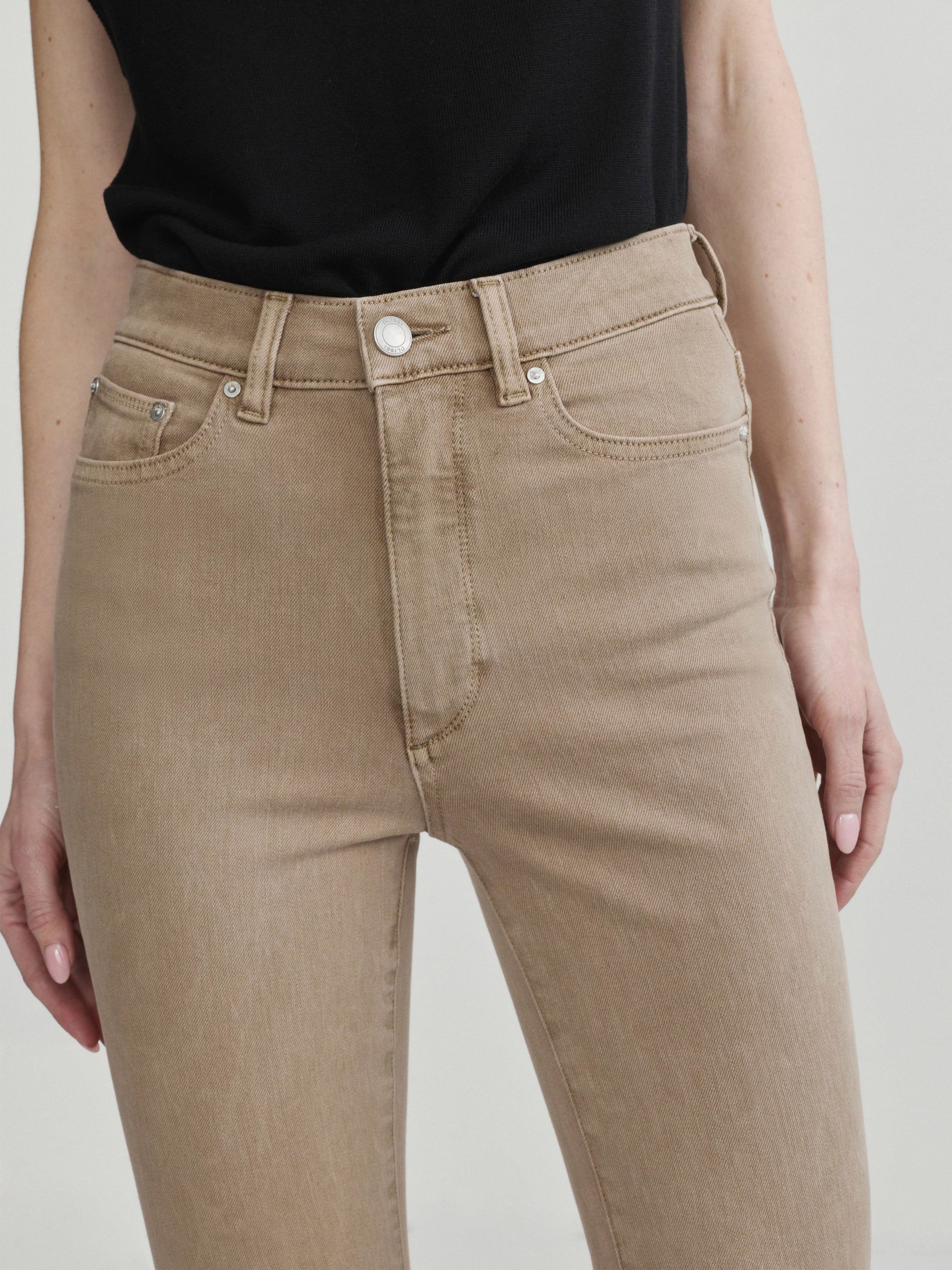 Bridget Boot jeans in Desert on a model, close-up front view of the waist and pocket in a studio.