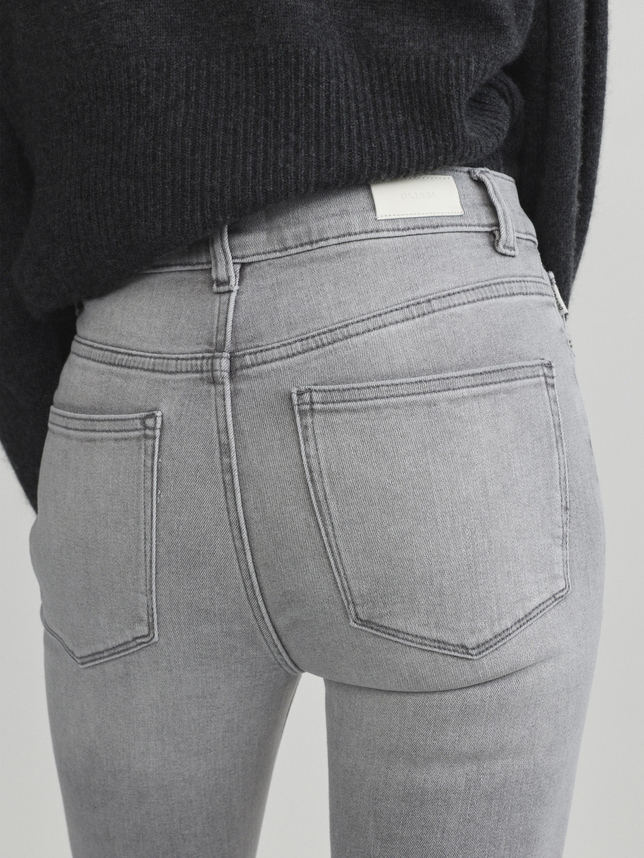 Bridget Boot jeans in Light Smoke on a model, close-up back view of the waist and pocket in a studio.