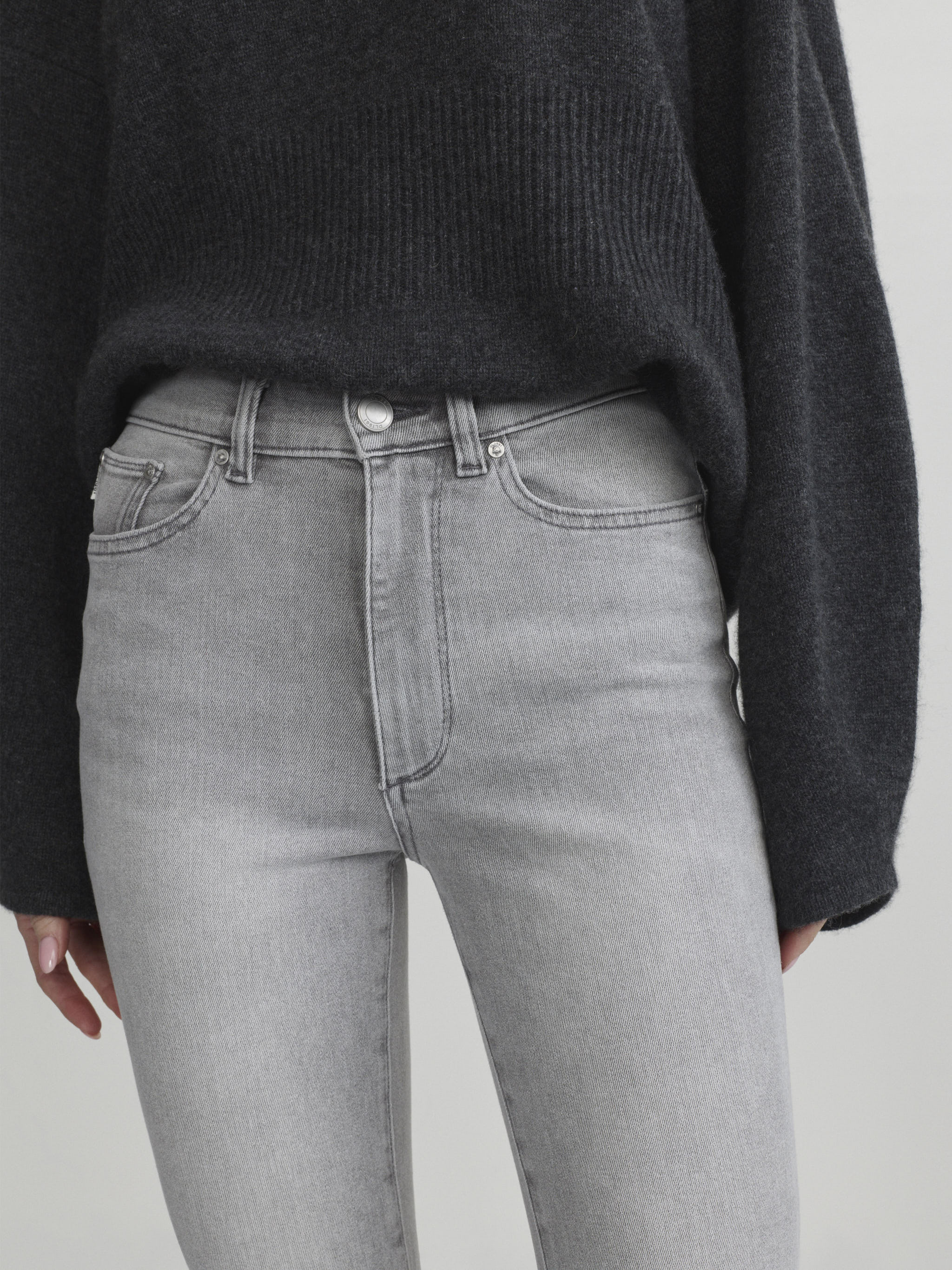 Bridget Boot jeans in Light Smoke on a model, close-up front view of the waist and pocket, studio.