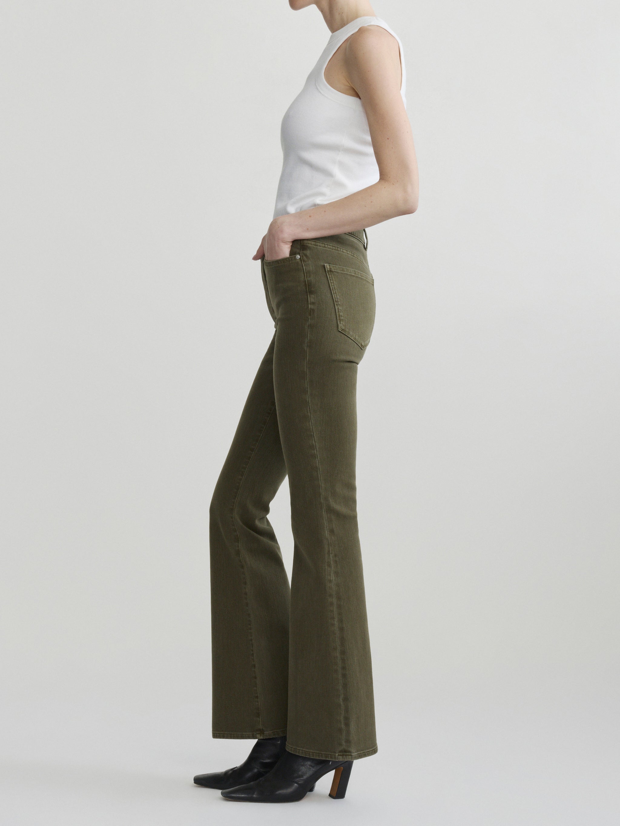 Bridget Boot jeans in Pine on a model with a white tank, full-length side view in a studio.