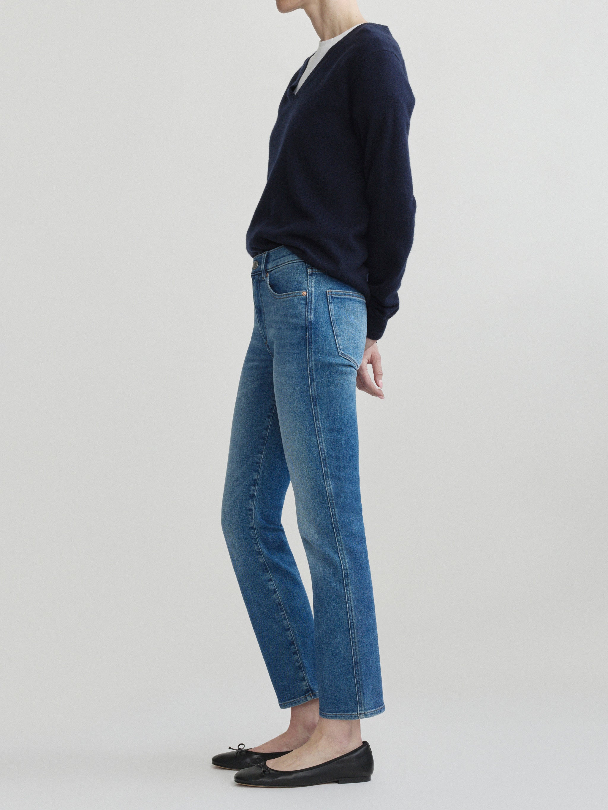 Mara Straight jeans in Crisp Air with a navy sweater on a model, full-length side view in studio.