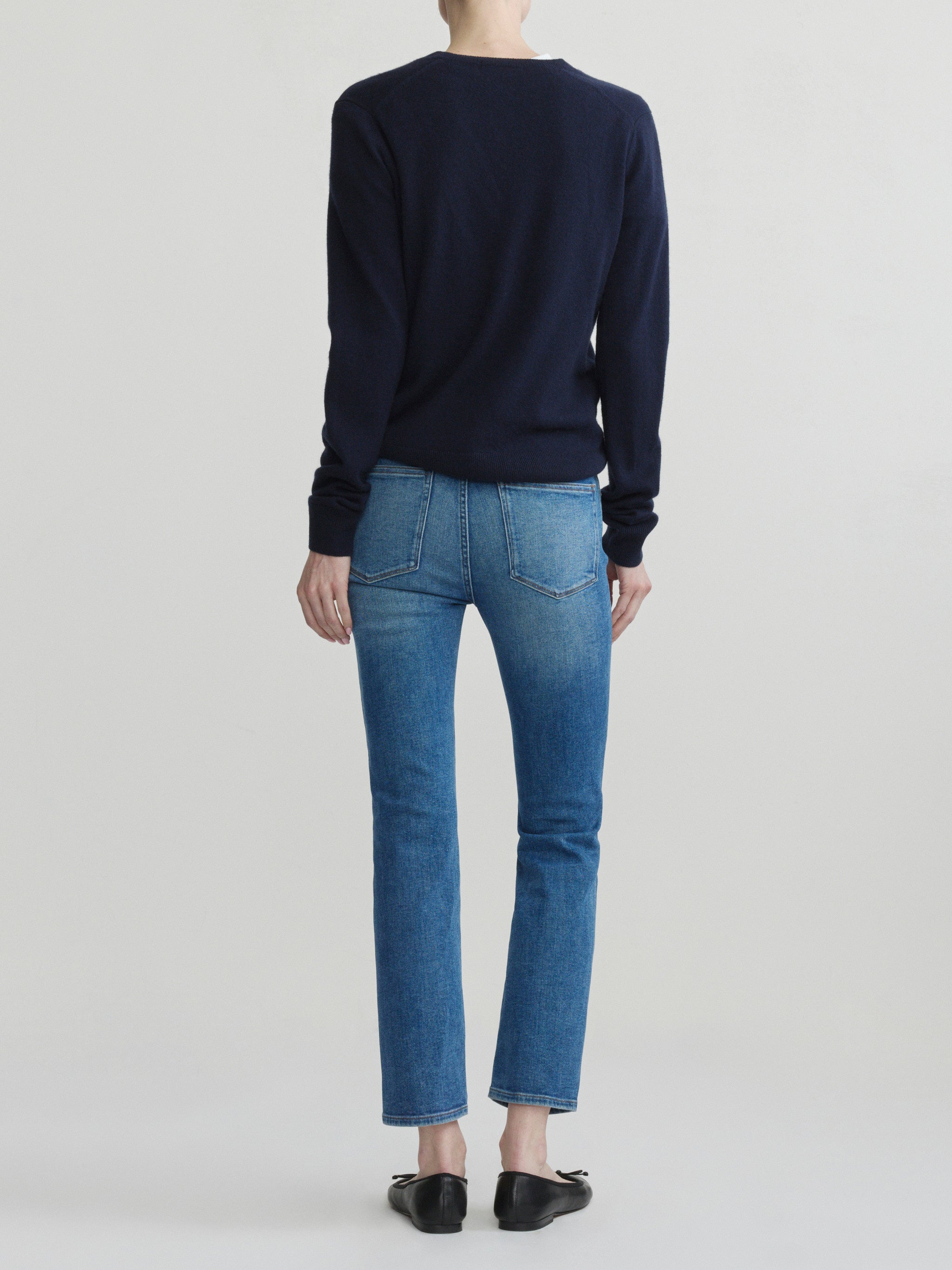 Mara Straight jeans in Crisp Air with a navy sweater on a model, full-length back view in studio.