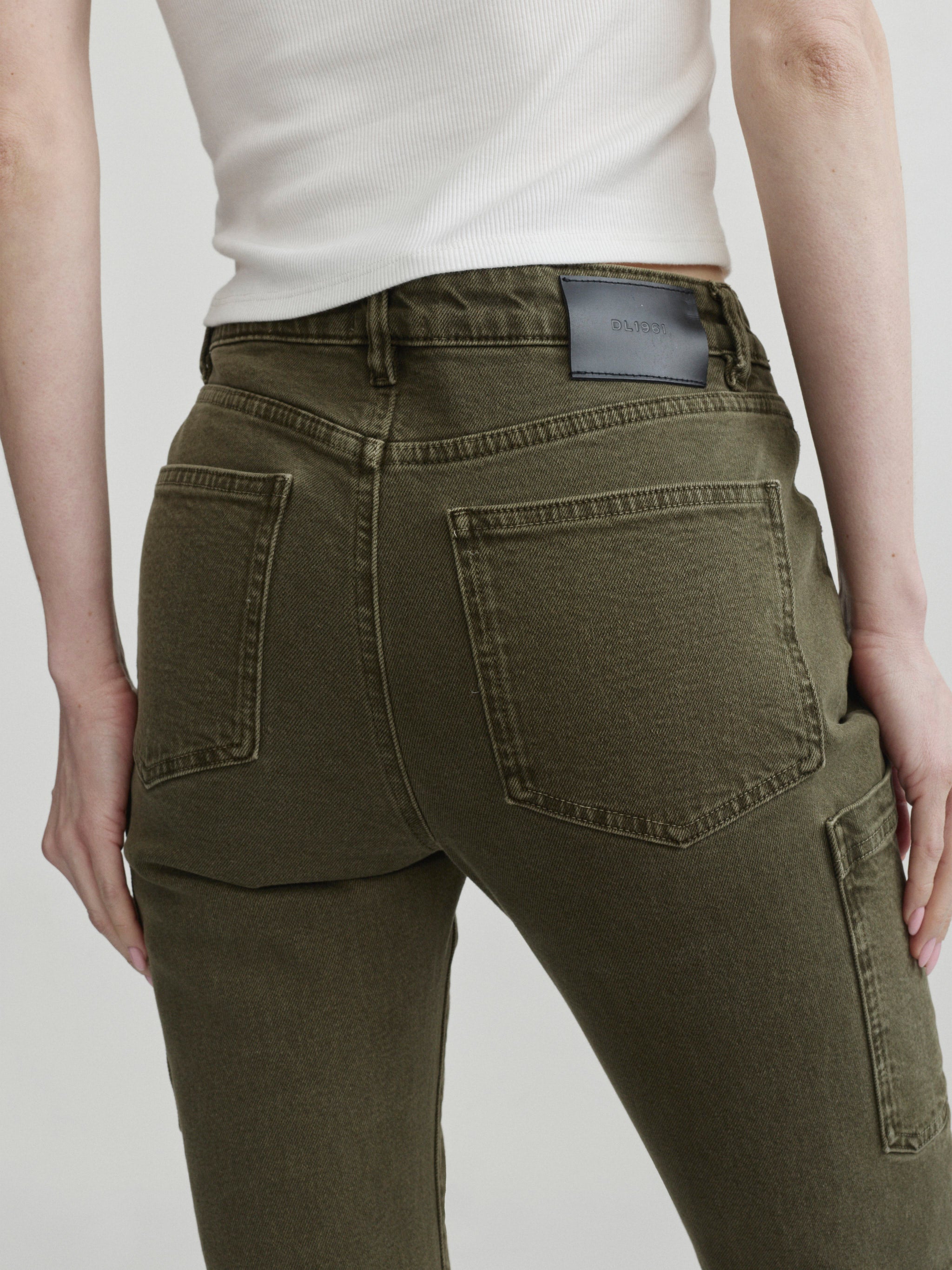 Devon Cigarette jeans in Pine on a model, close-up back view of pockets in studio.