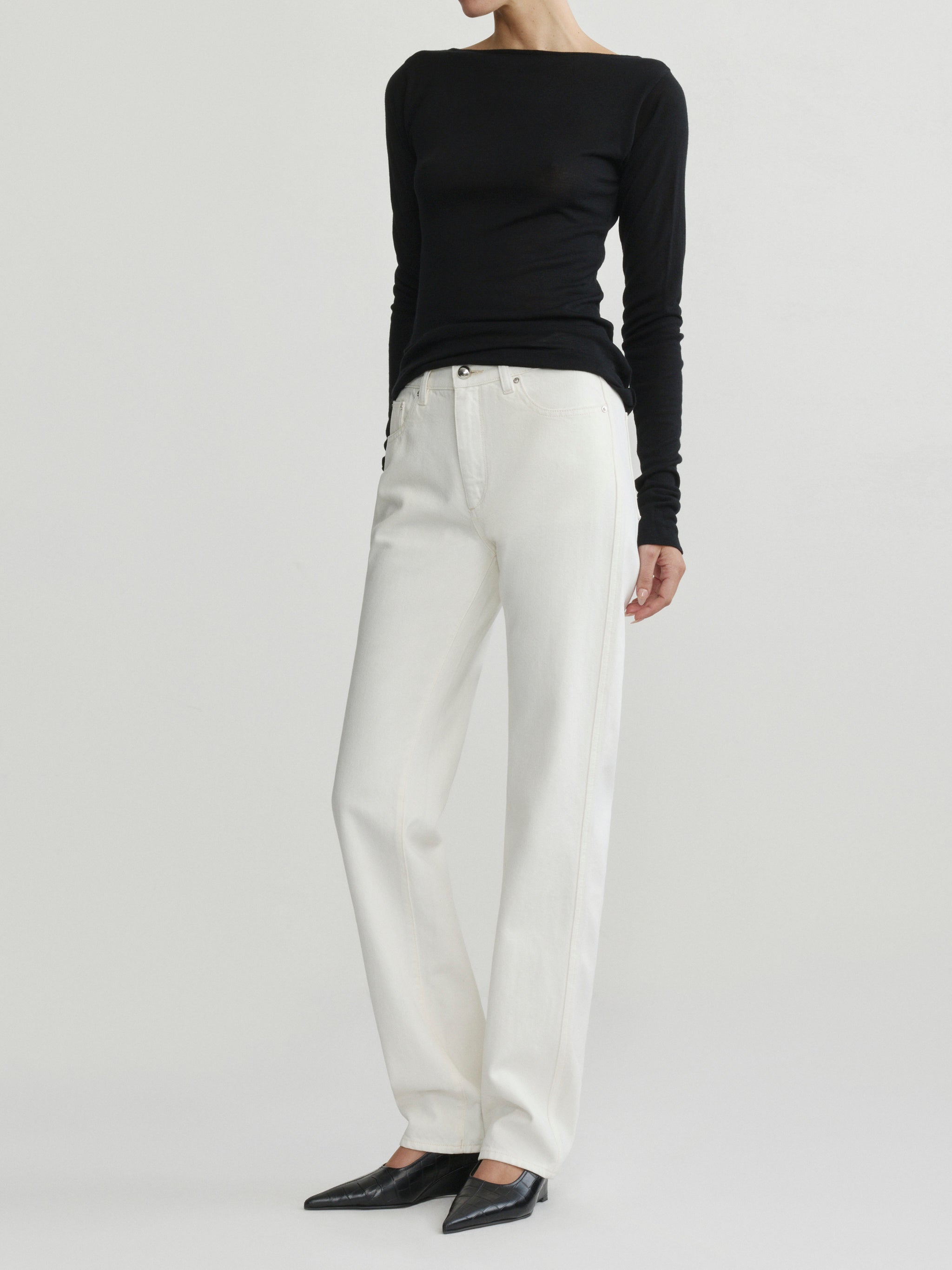 Cate Slim Leg jeans in Eggshell with black top on a model, full-length three-quarter view in studio.