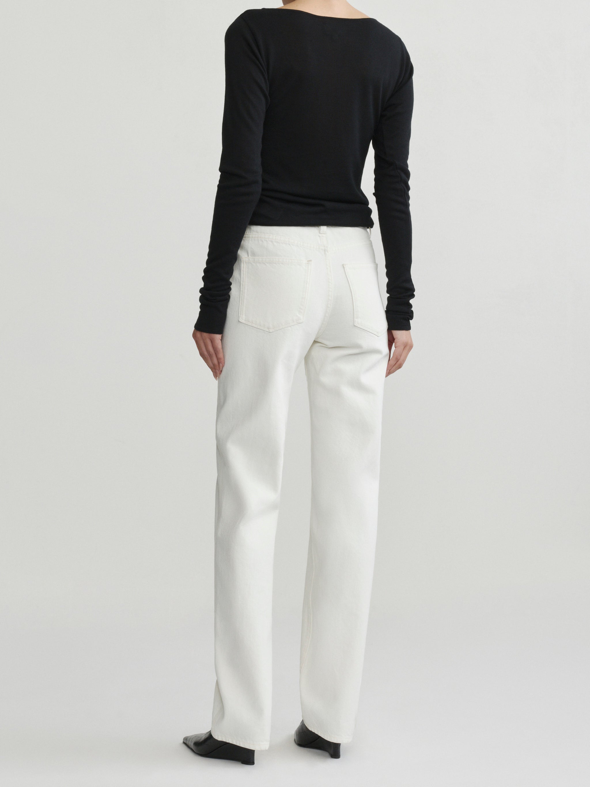 Cate Slim Leg jeans in Eggshell with black top on a model, full-length back view in studio.