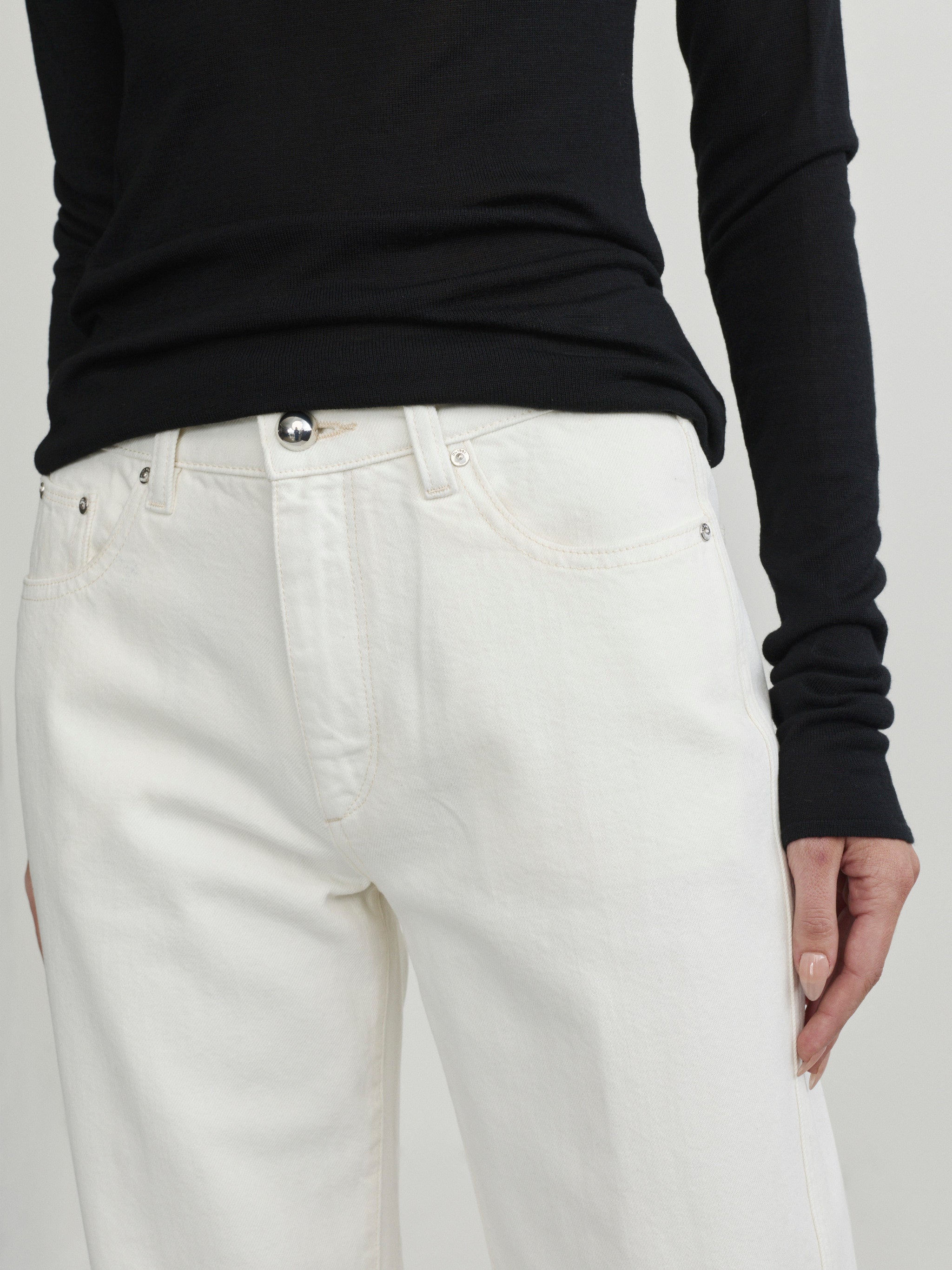 Cate Slim Leg jeans in Eggshell on a model, close-up front view of waist in studio.