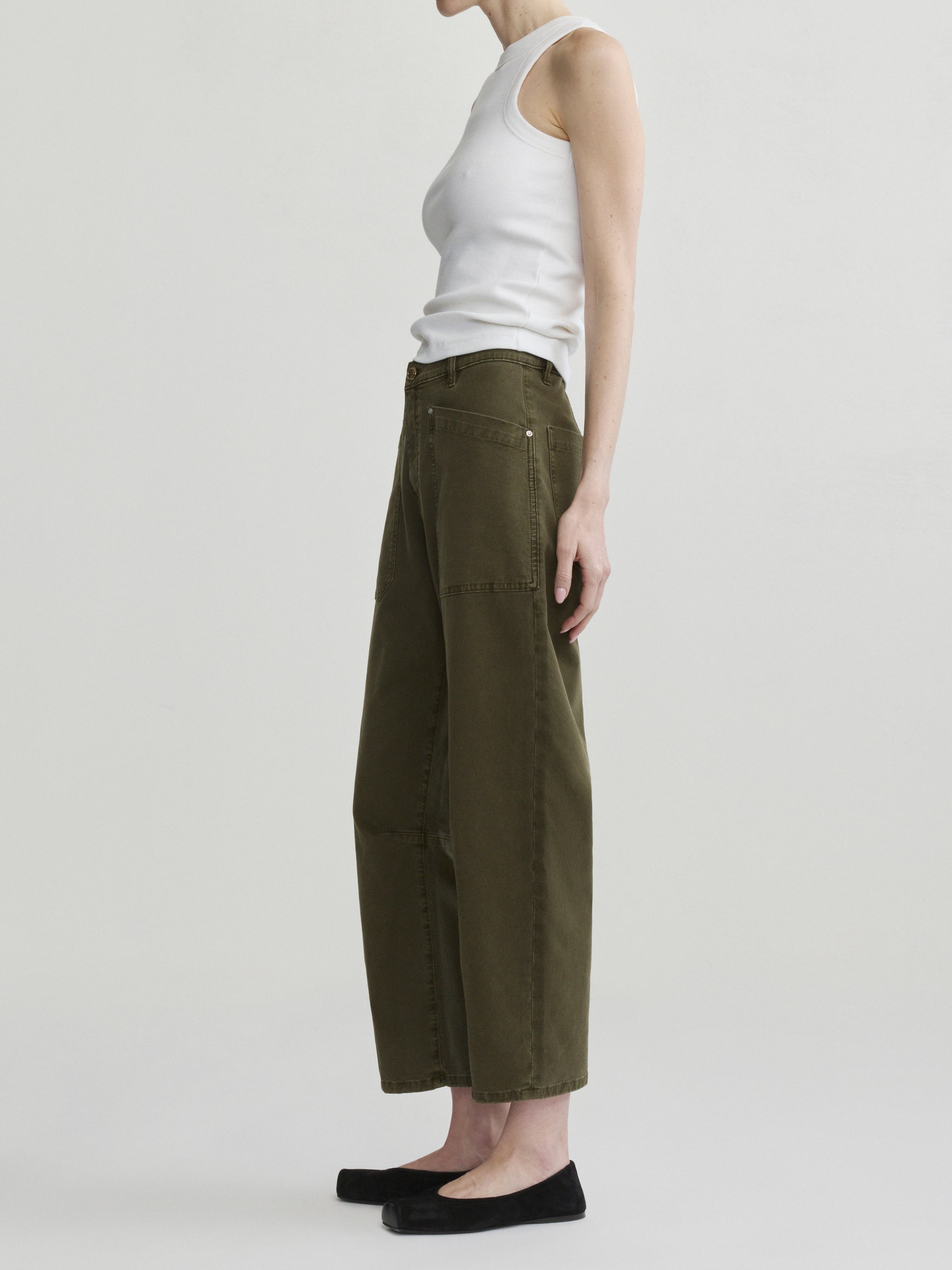 Bilie Easy Barrel jeans in Pine on a model with white tank top, side view in studio.