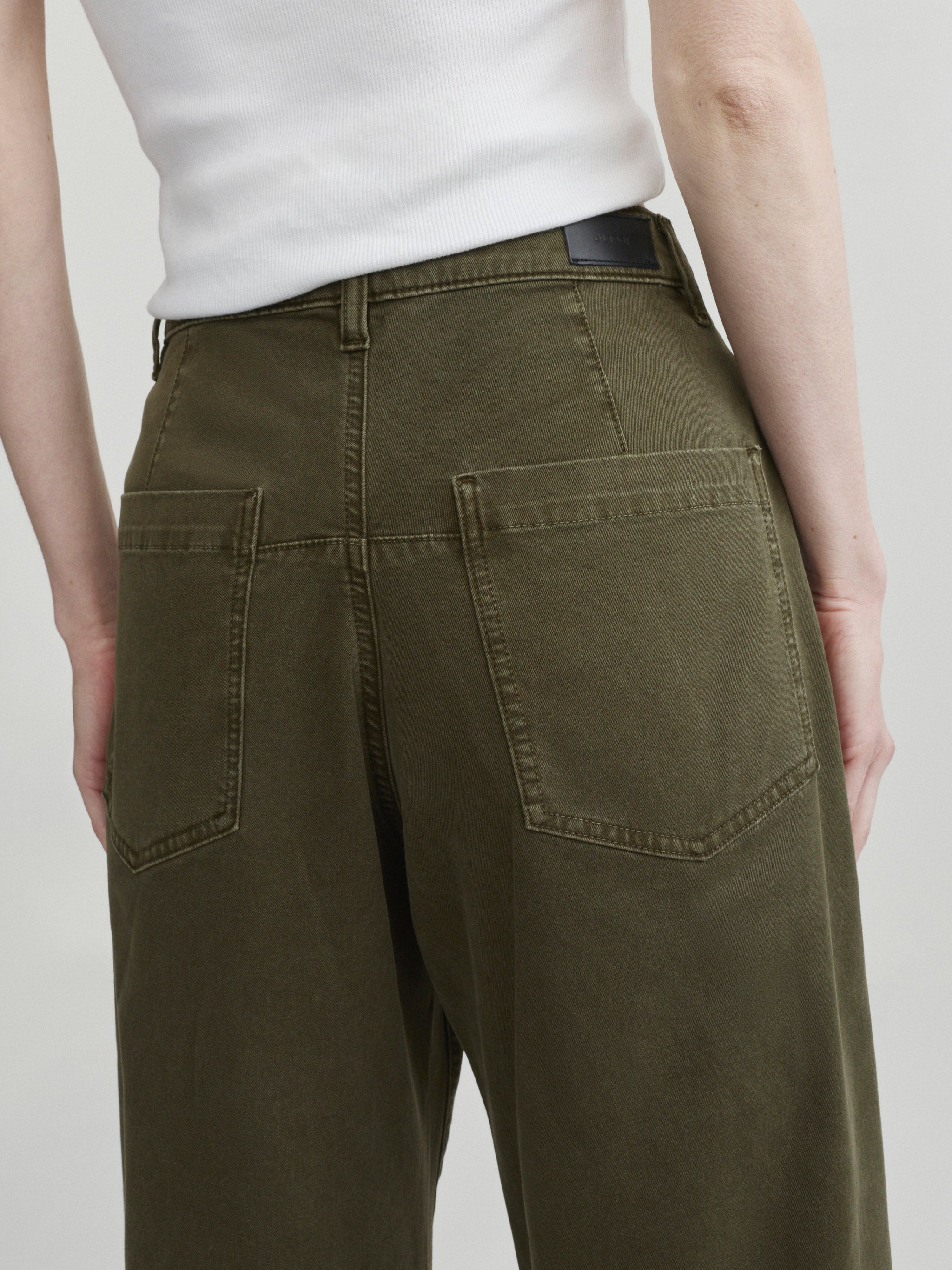 Bilie Easy Barrel jeans in Pine on a model with white top, close-up back view of pockets.