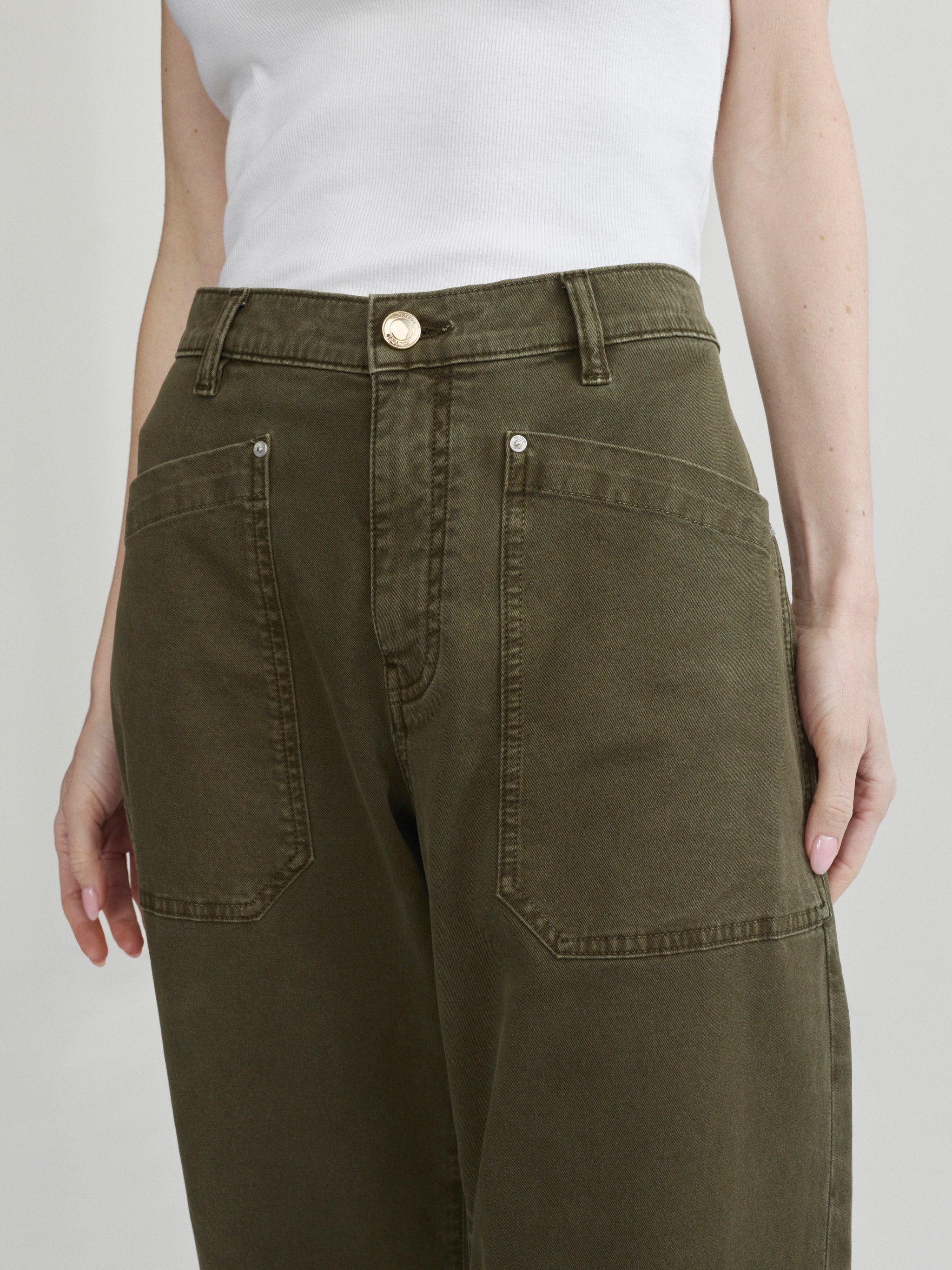 Bilie Easy Barrel jeans in Pine on a model with white top, close-up front view of waist and pockets.