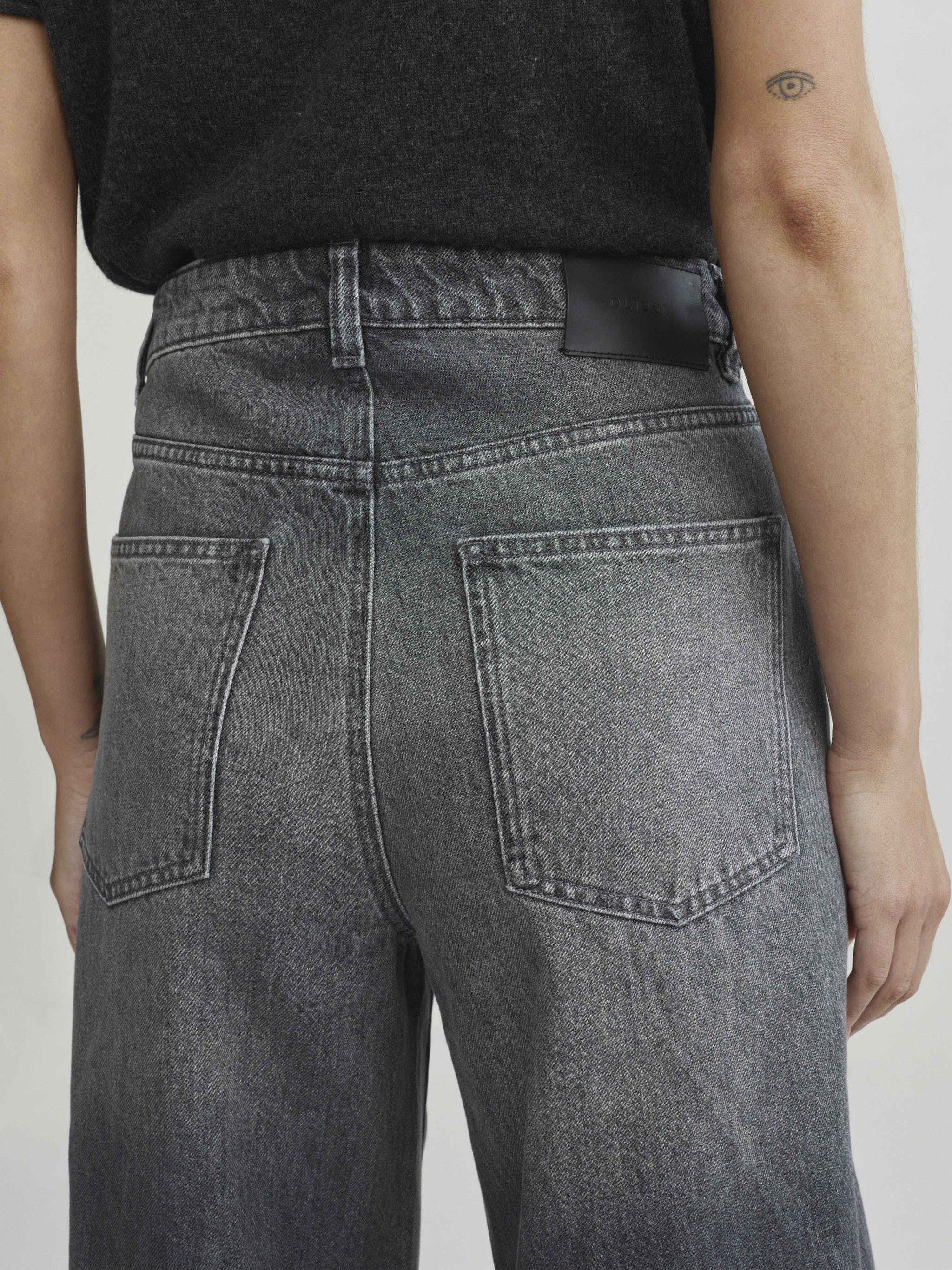 Miro Barrel jeans in Ash Grey on a model with dark tee, close-up back view of pockets.