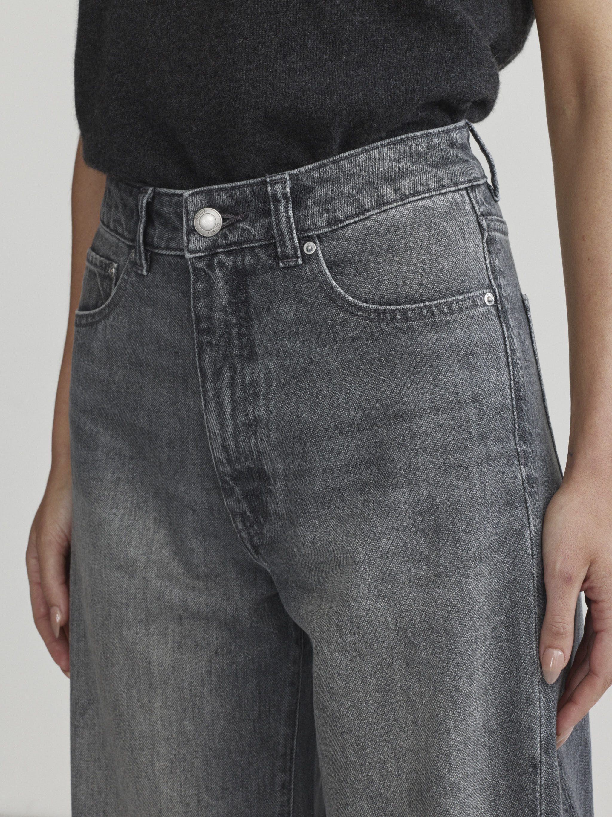 Miro Barrel jeans in Ash Grey on a model with dark tee, close-up front view of waist.