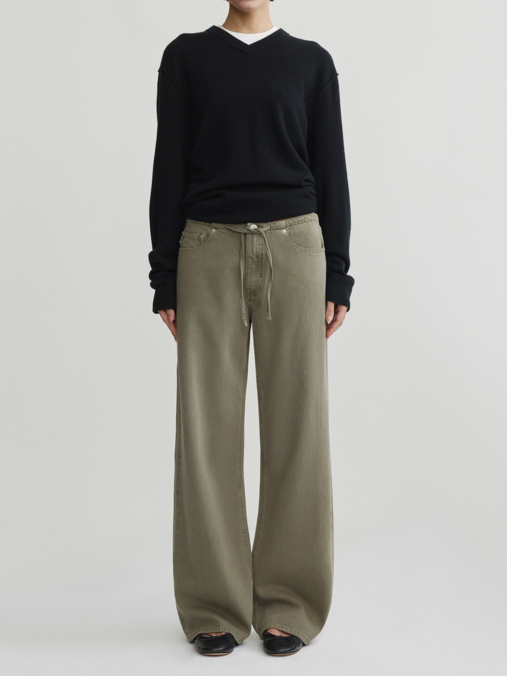 Sienna Low-Slung Wide Leg jeans in Clover Aura on a model with black V-neck sweater, full-length front view.