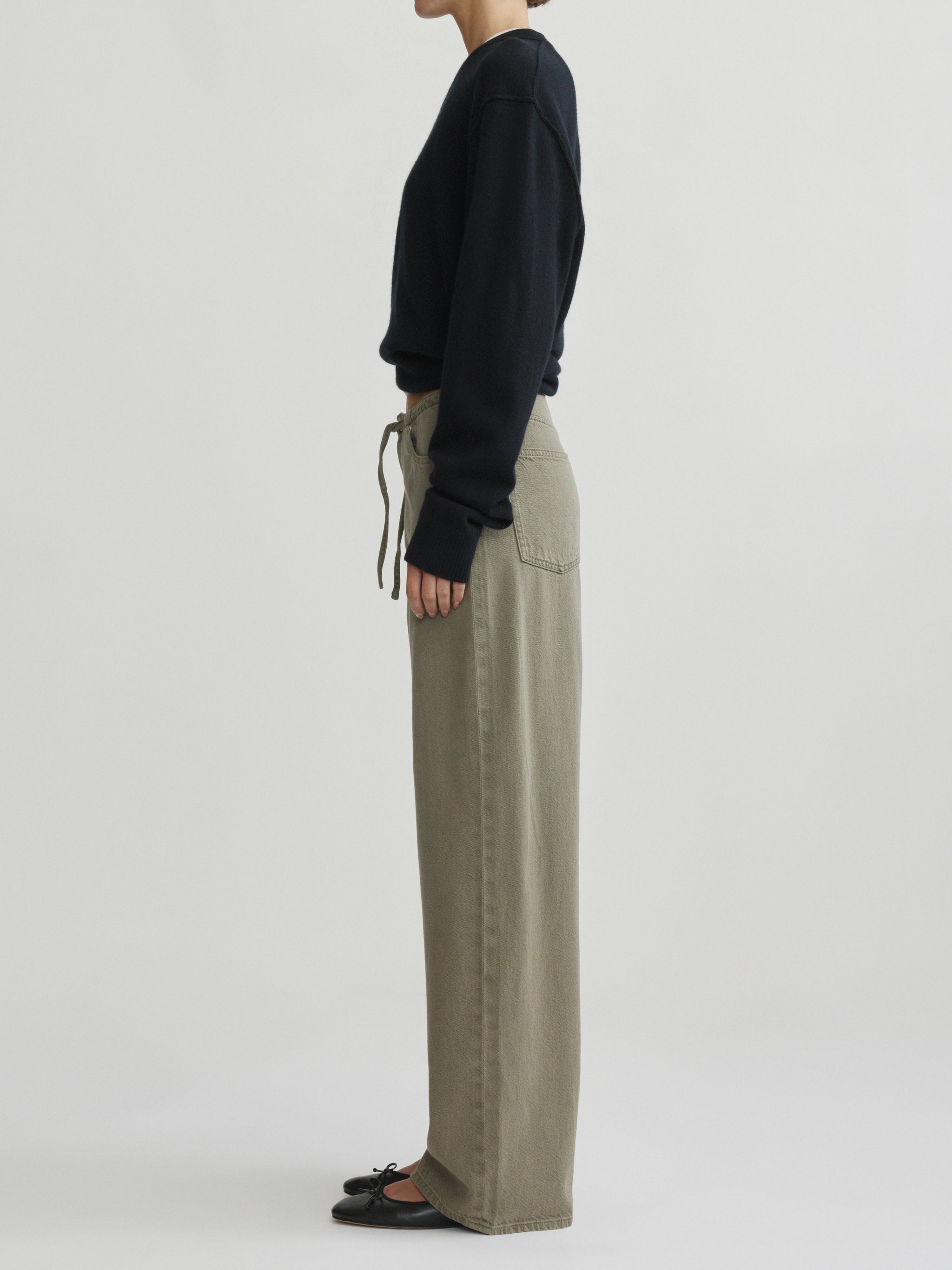 Sienna Low-Slung Wide Leg jeans in Clover Aura on a model in black sweater, full-length side view.
