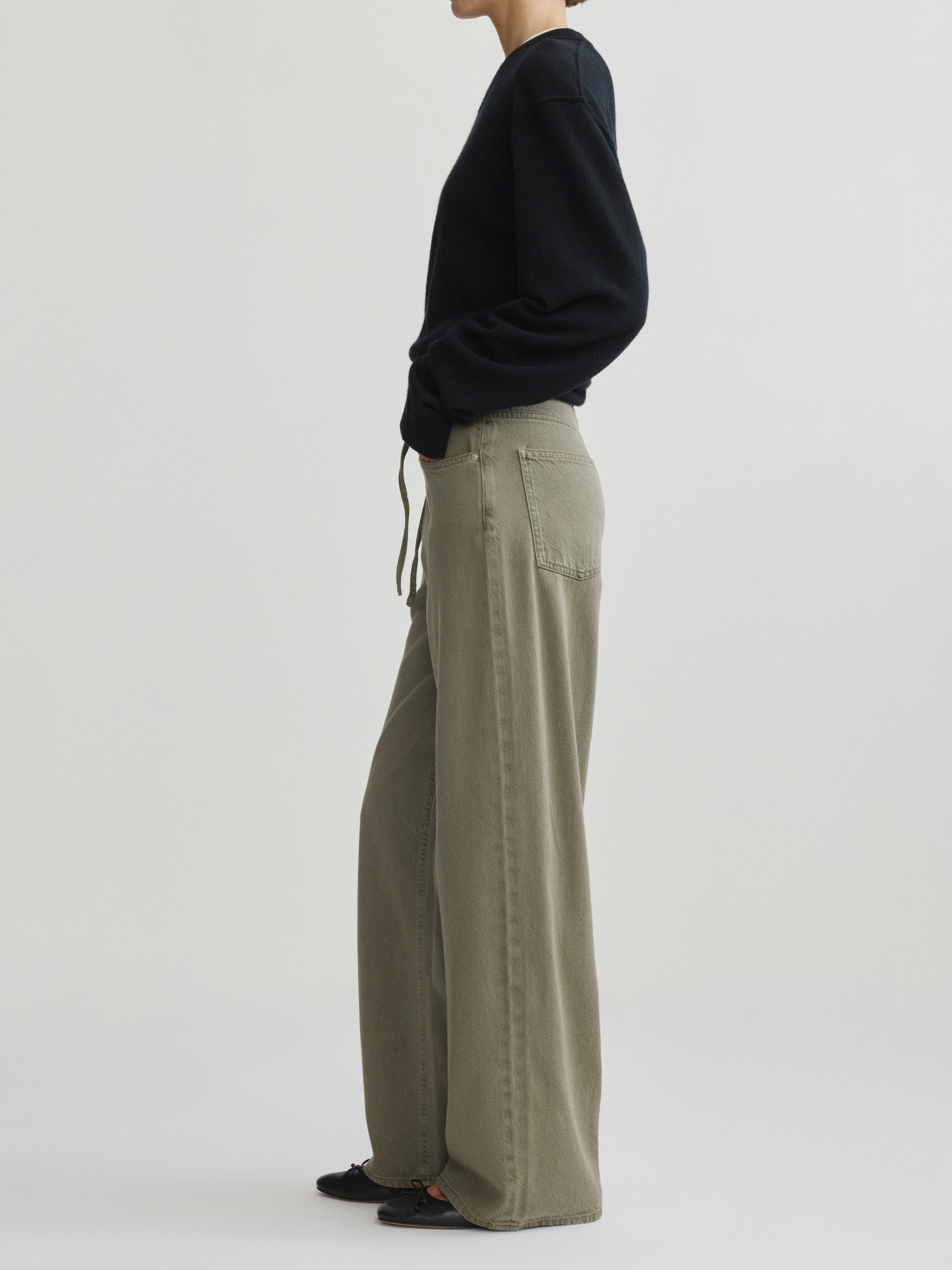 Sienna Low-Slung Wide Leg jeans in Clover Aura on a model in black sweater, full-length side view.