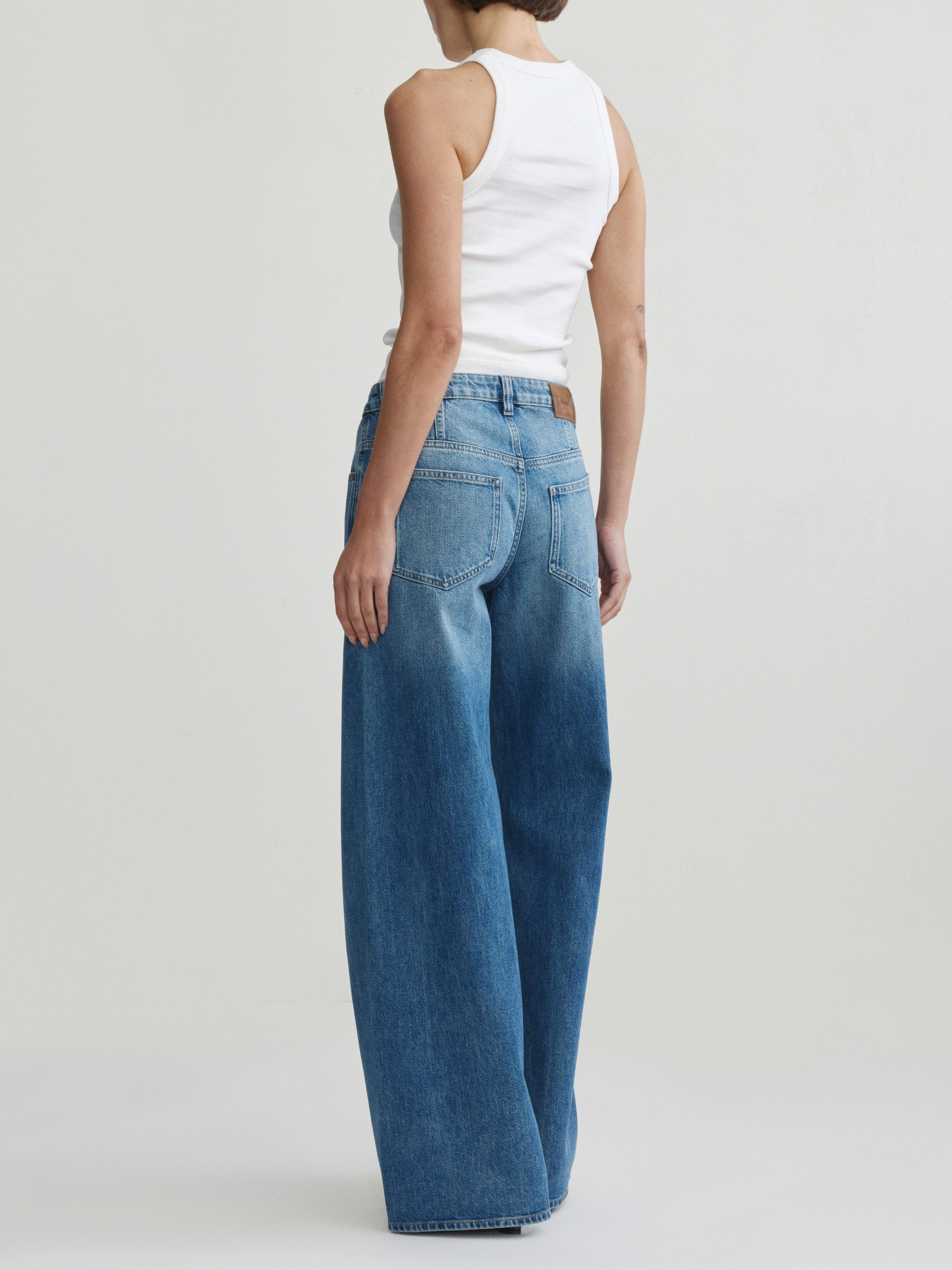 Alex Baggy Wide Leg jeans in Authentic on a model in white tank top, full-length back view.