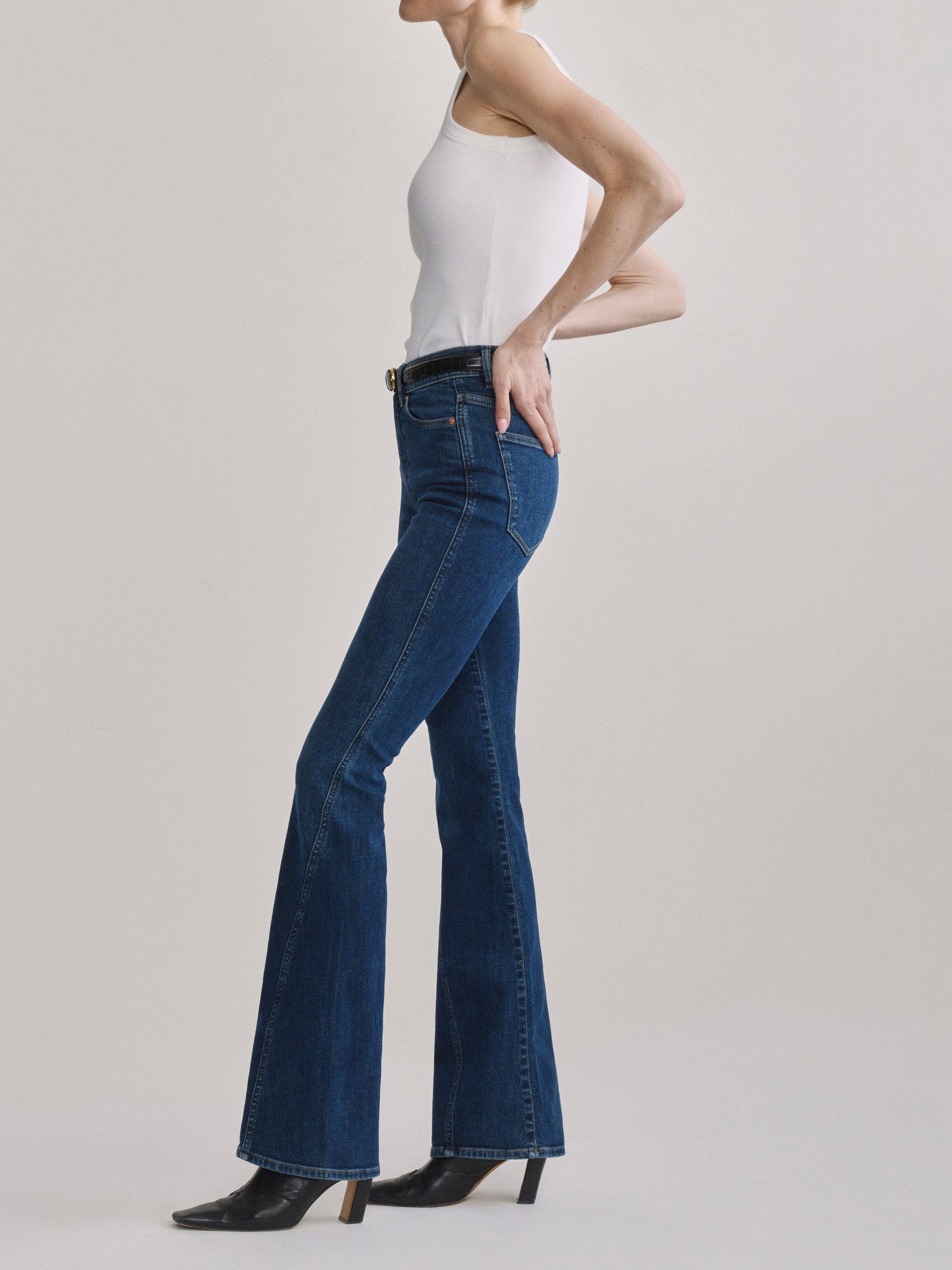Bridget Boot Breeze Seamed jeans with the High Neck Ribbed Tank in White, full-length side profile in a studio.