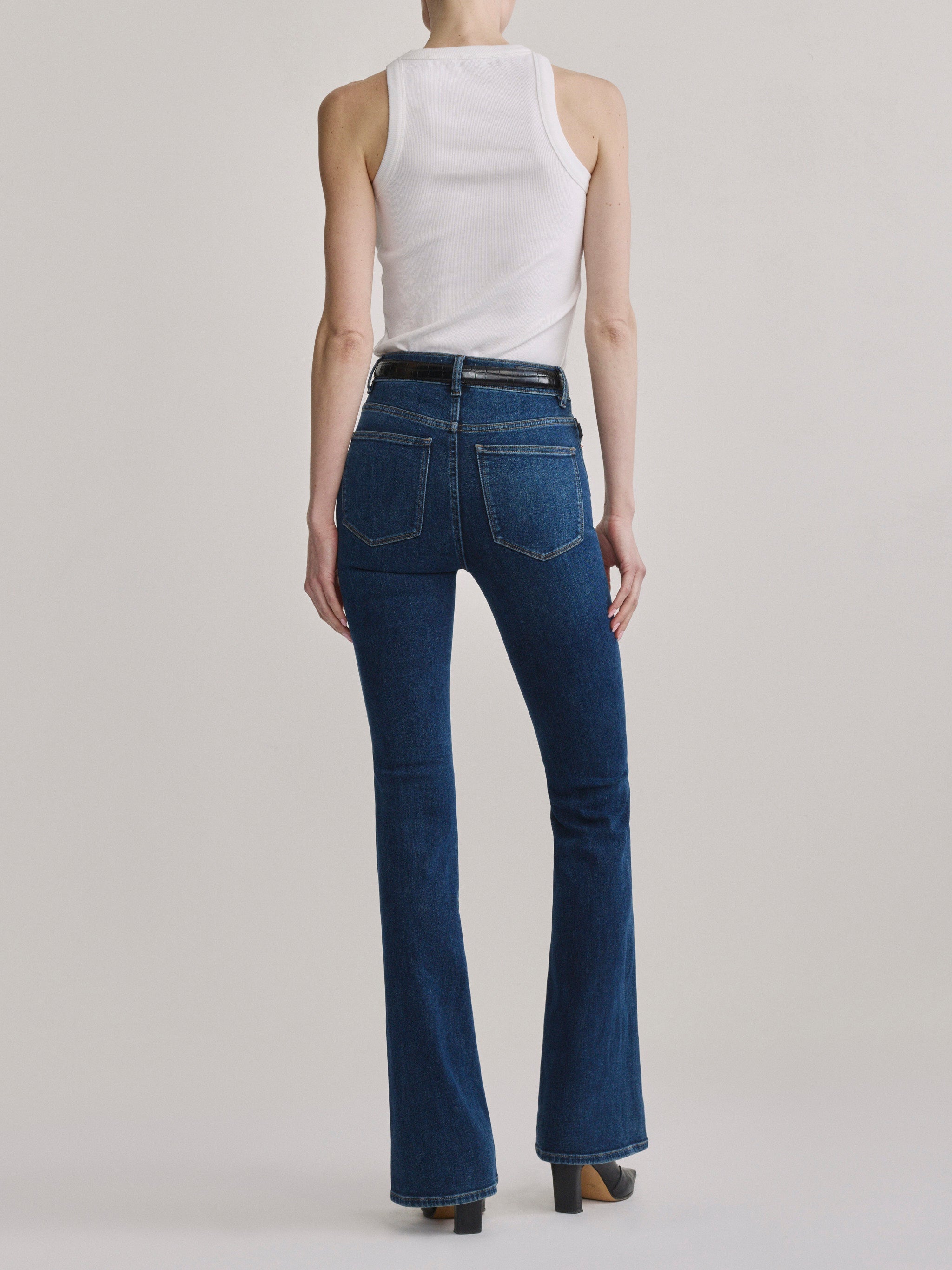 Bridget Boot Breeze Seamed jeans with the High Neck Ribbed Tank in White, full-length back view in a studio.