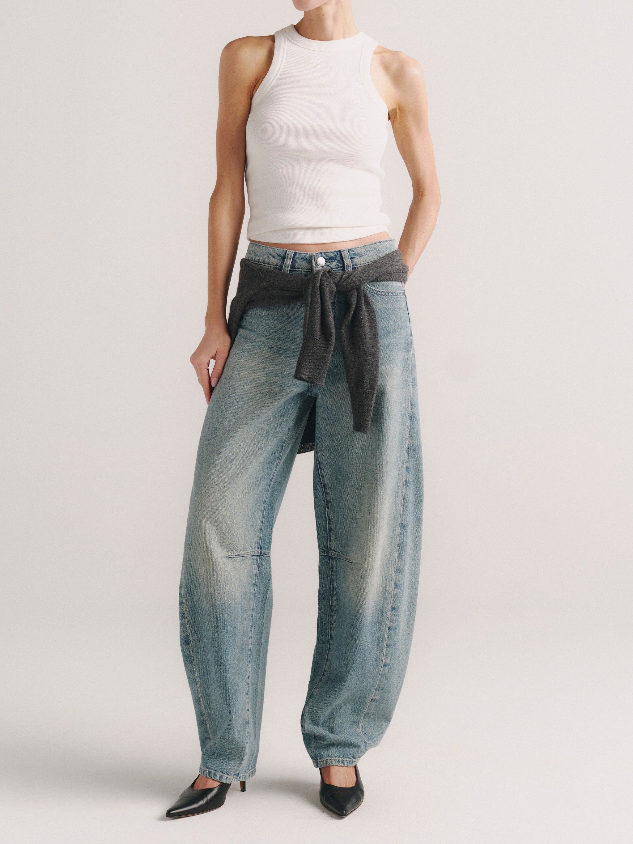 Miro Barrel jeans in Worn Day on a model in white tank top with sweater tied at waist, full-length front.