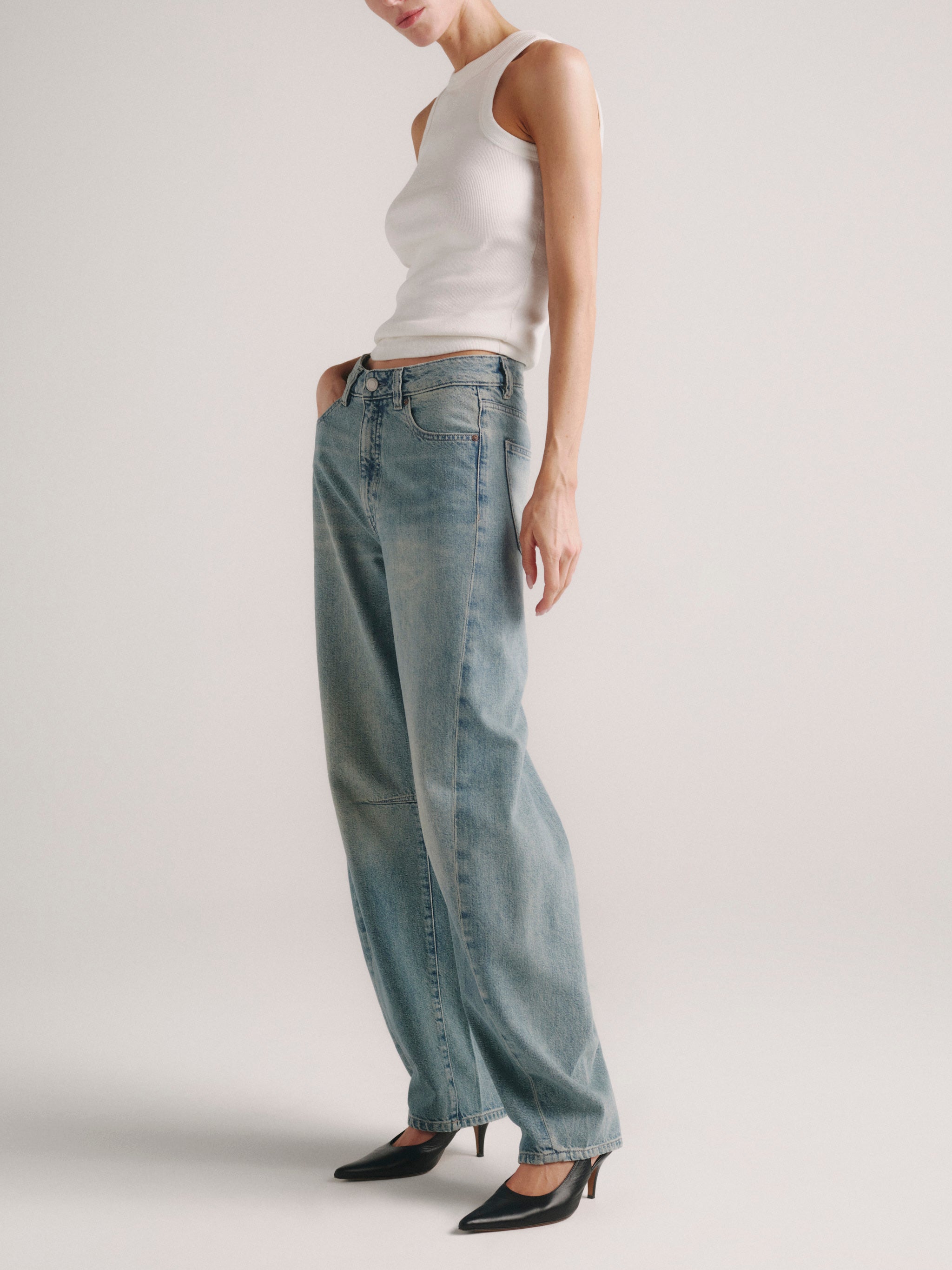 Miro Barrel jeans in Worn Day on a model in white tank top, full-length side view.