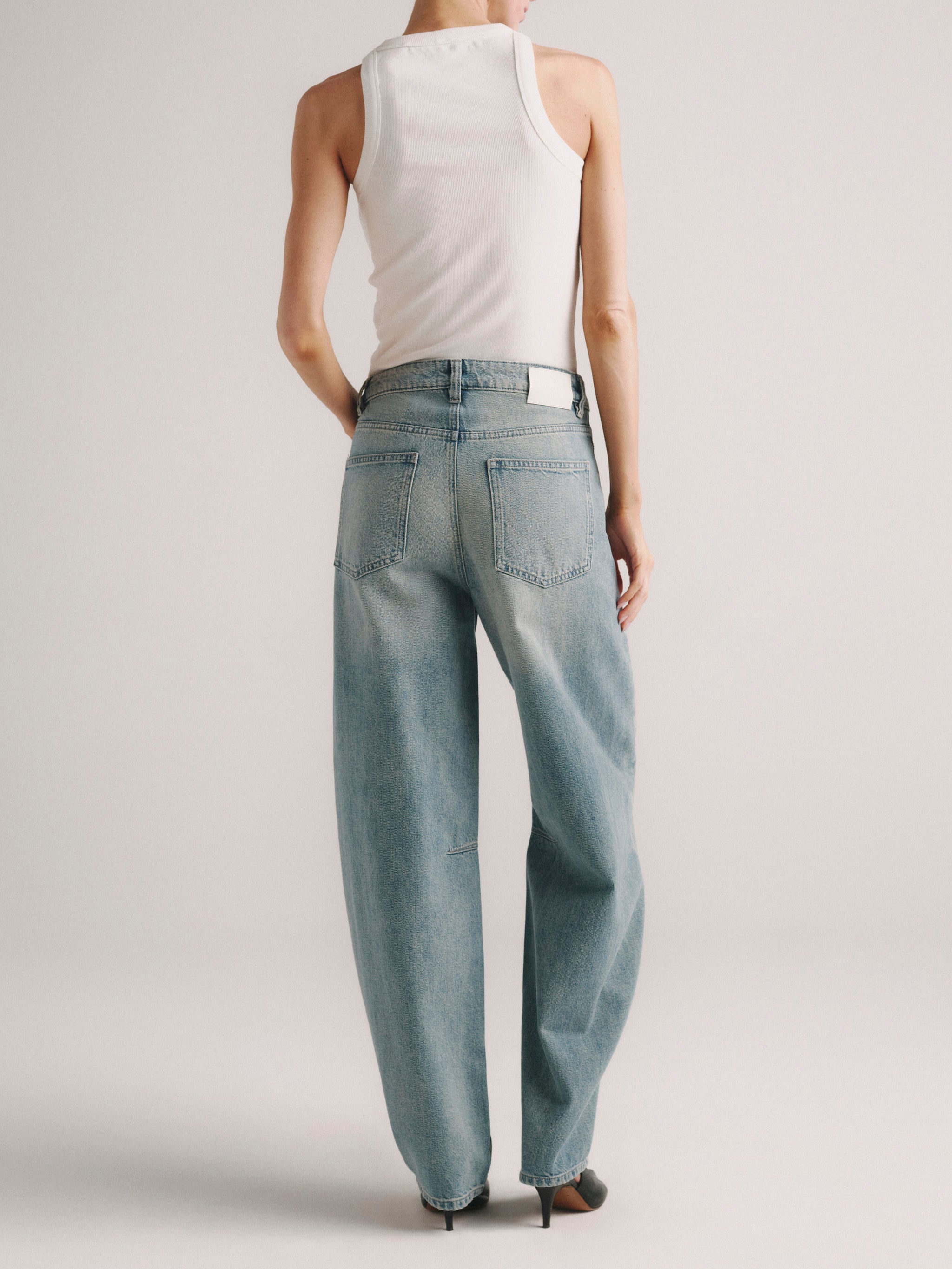 Miro Barrel jeans in Worn Day on a model in white tank top, full-length back view.