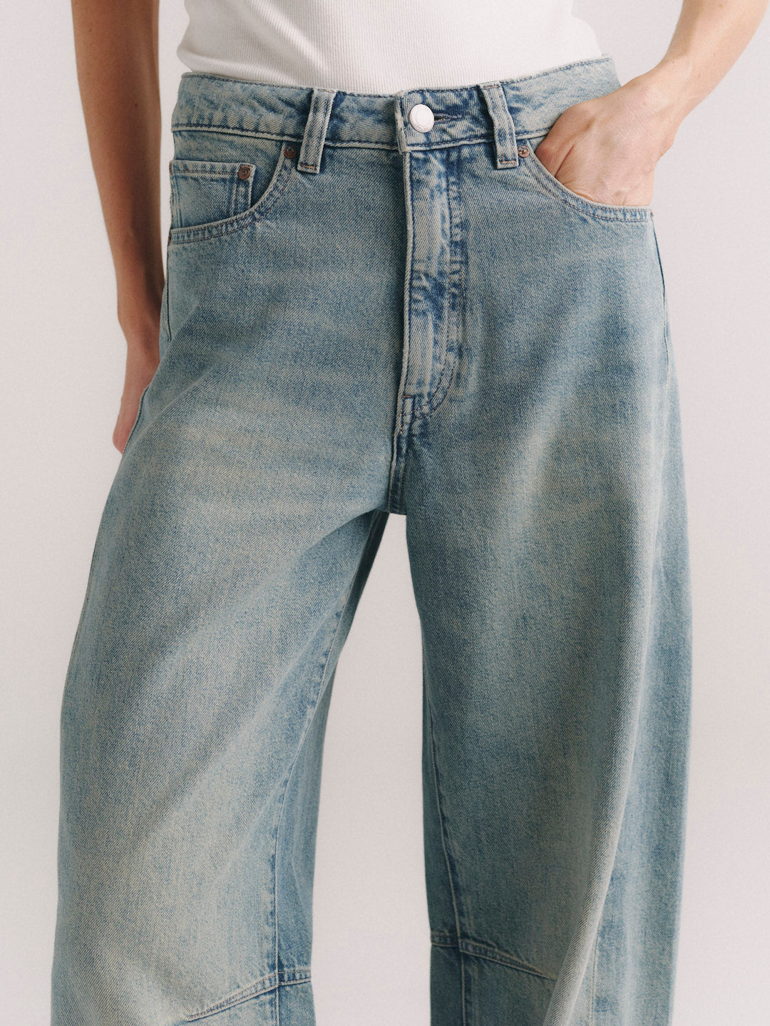 Miro Barrel jeans in Worn Day, close-up of front waistband, pocket, and curved barrel-leg seam.