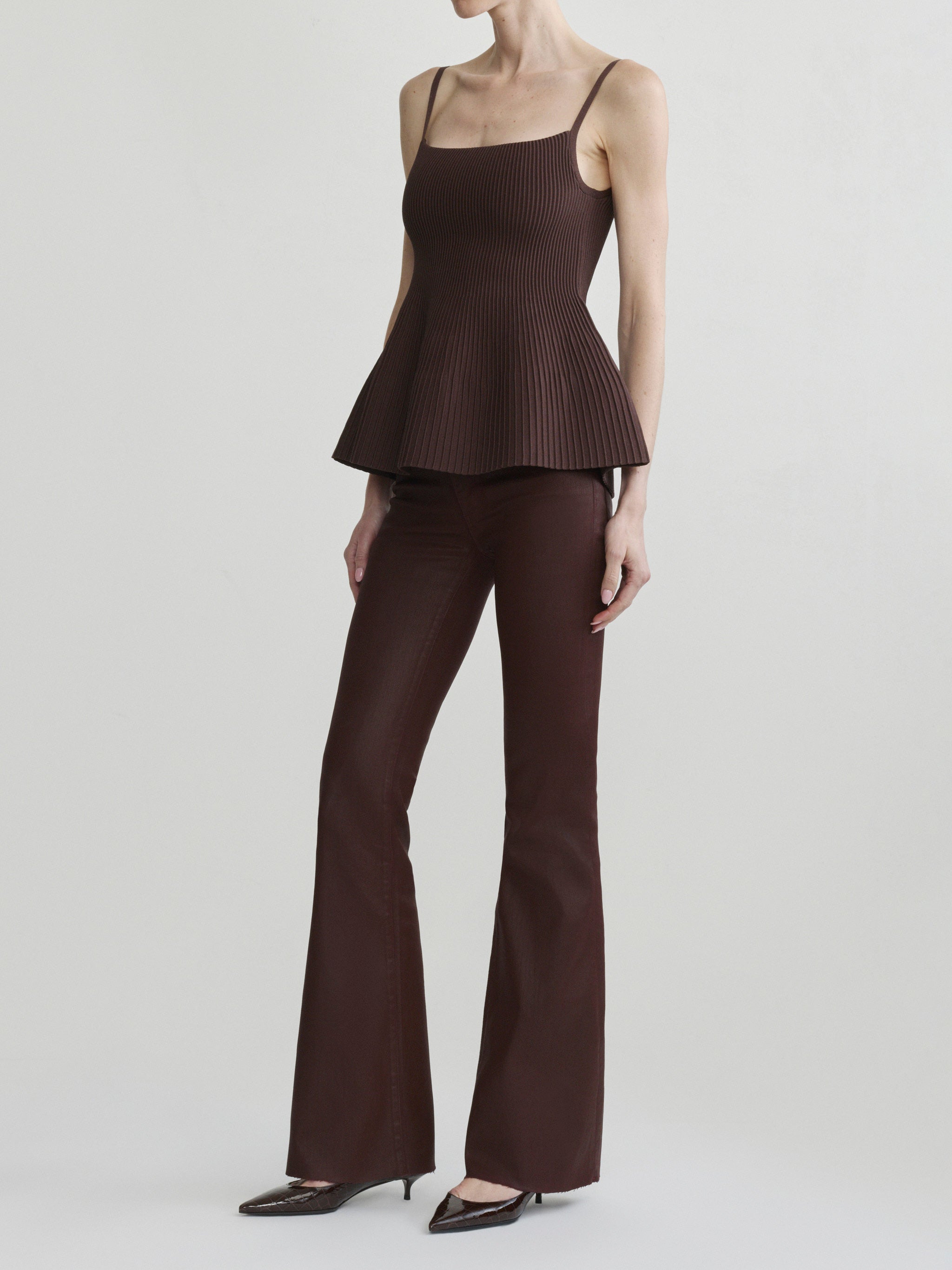 Bridget Boot jeans in Vin Rouge Coated with Truffle Peplum Tank, model three-quarter view, full-length.