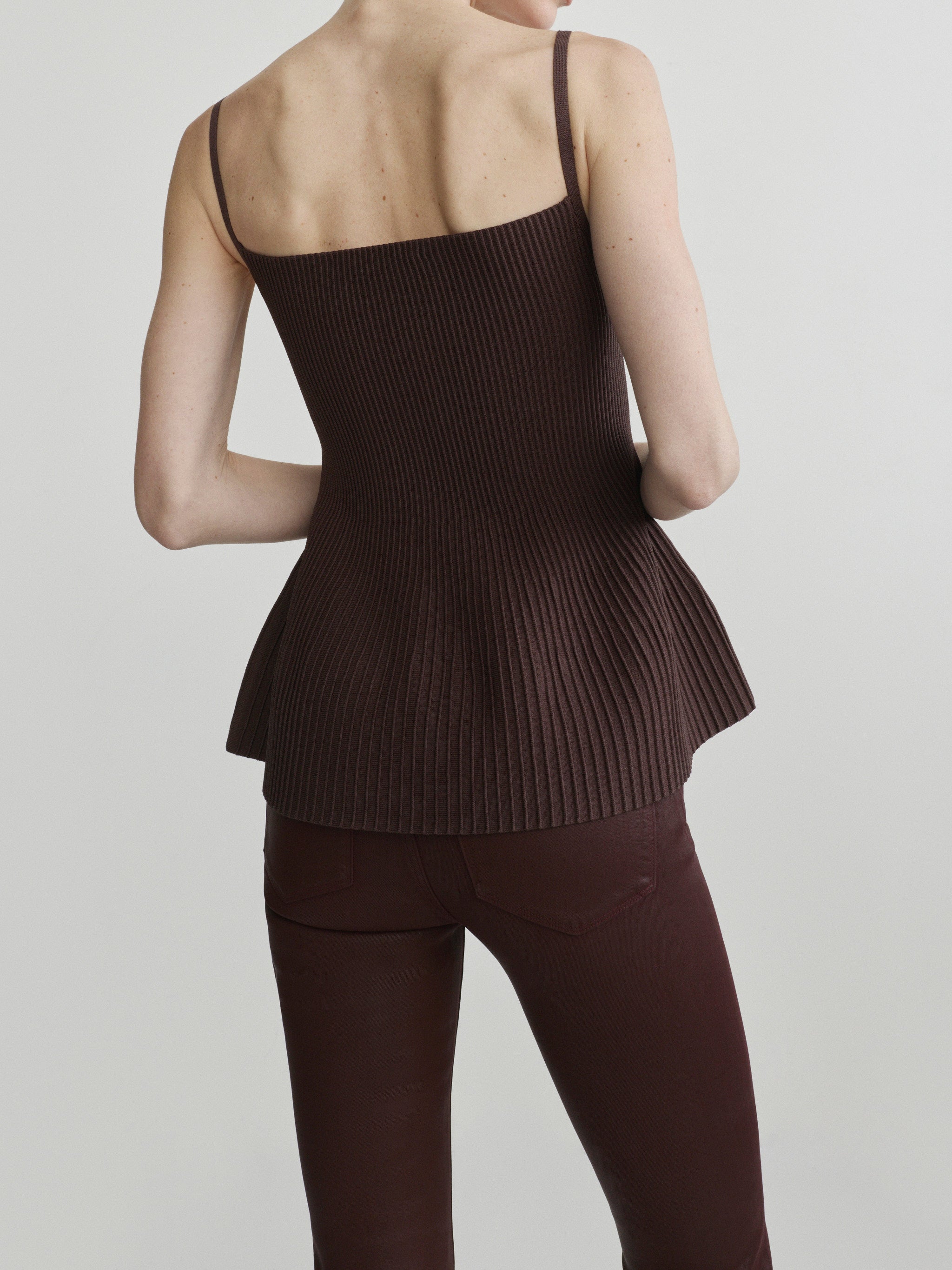 Bridget Boot jeans in Vin Rouge Coated with Truffle Peplum Tank, model back view, upper-body crop.