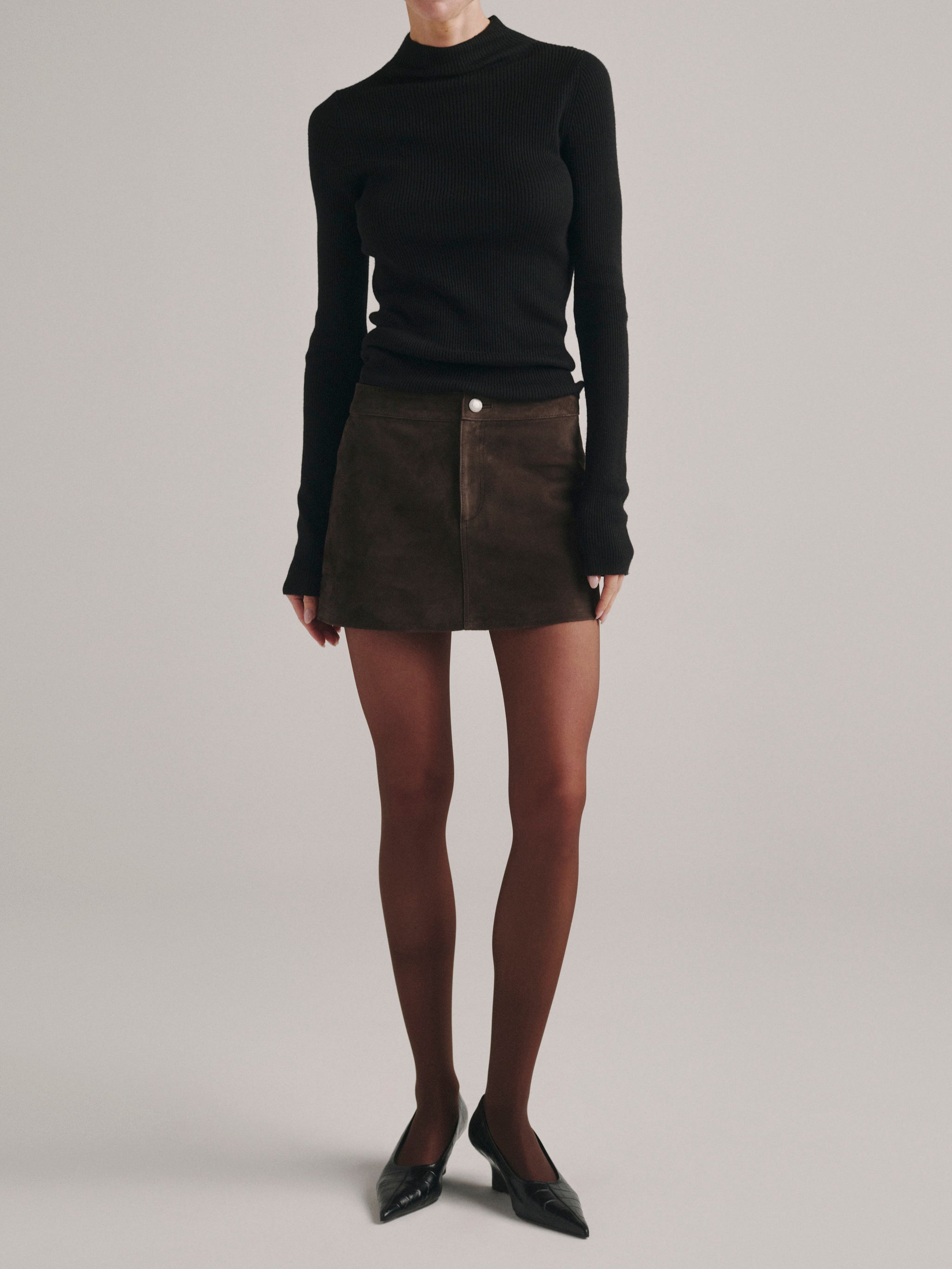 DL1961 Avalon Mini Low-Rise Suede Skirt in brown Tobacco Suede with black top and tights, front view.