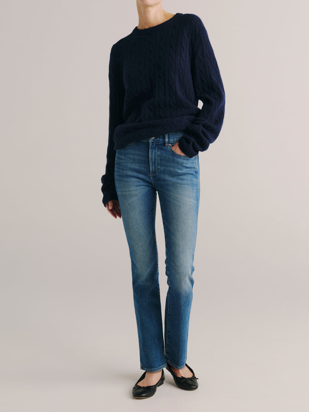Mara jeans in Crisp Air with a navy cable-knit sweater, full-length front view with ballet flats, studio.