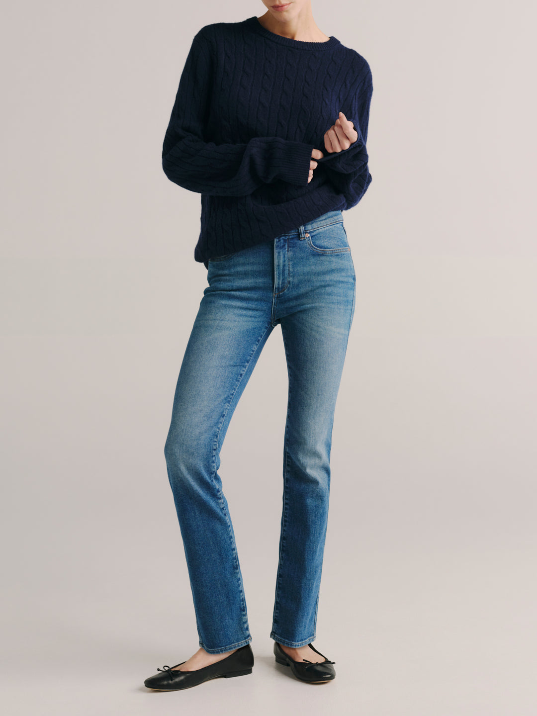 Mara jeans in Crisp Air with a navy cable-knit sweater, full-length front three-quarter view in a studio.
